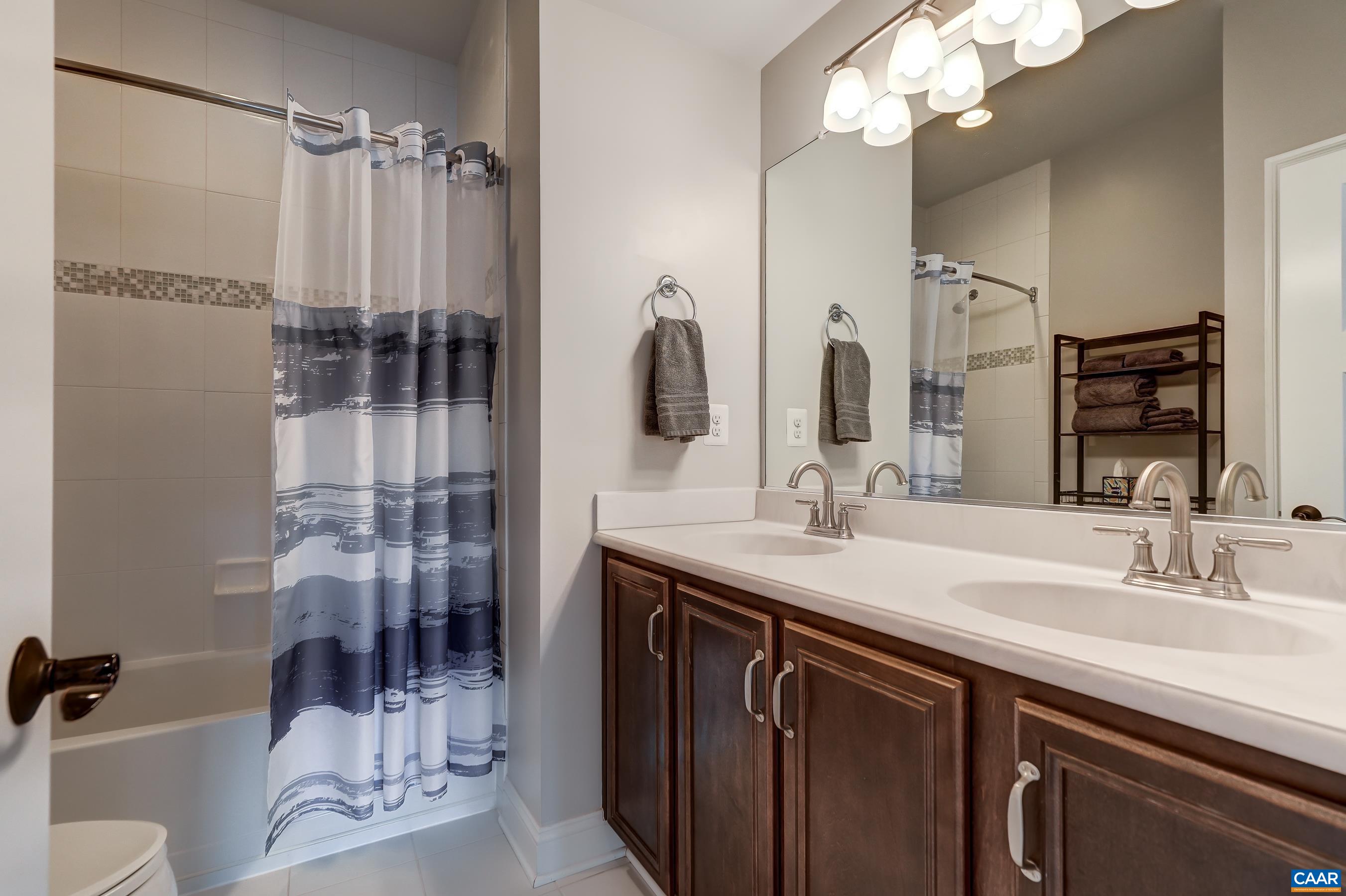 Hall bathroom with double sink vanity and tub/shower combo.
