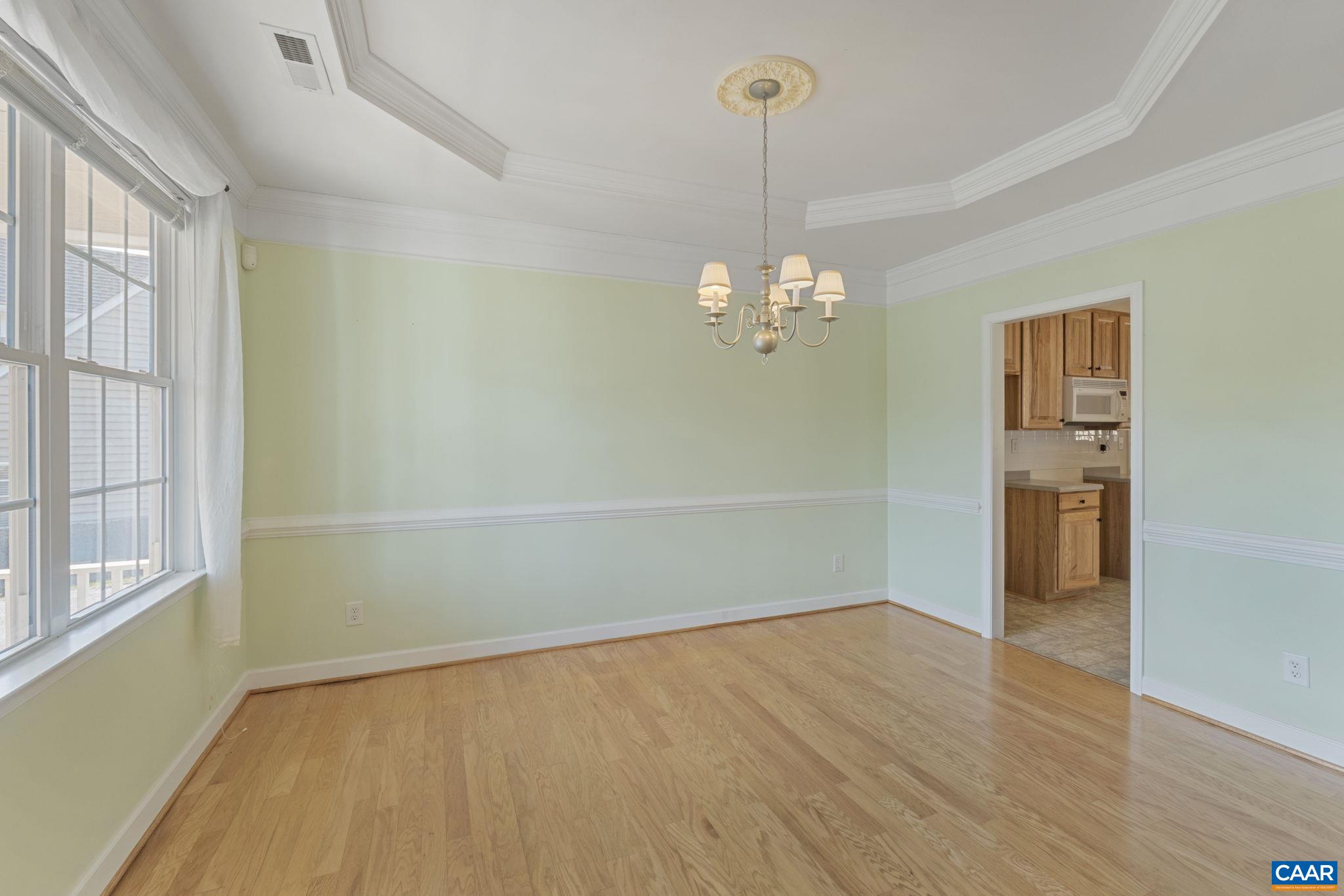 Dining room off foyer with chair rail, vaulted ceiling.