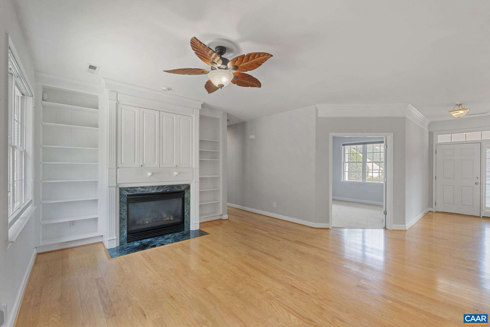 Family room ceiling fan, fireplace, built-ins, and double doors leading to bedroom or home office/study.