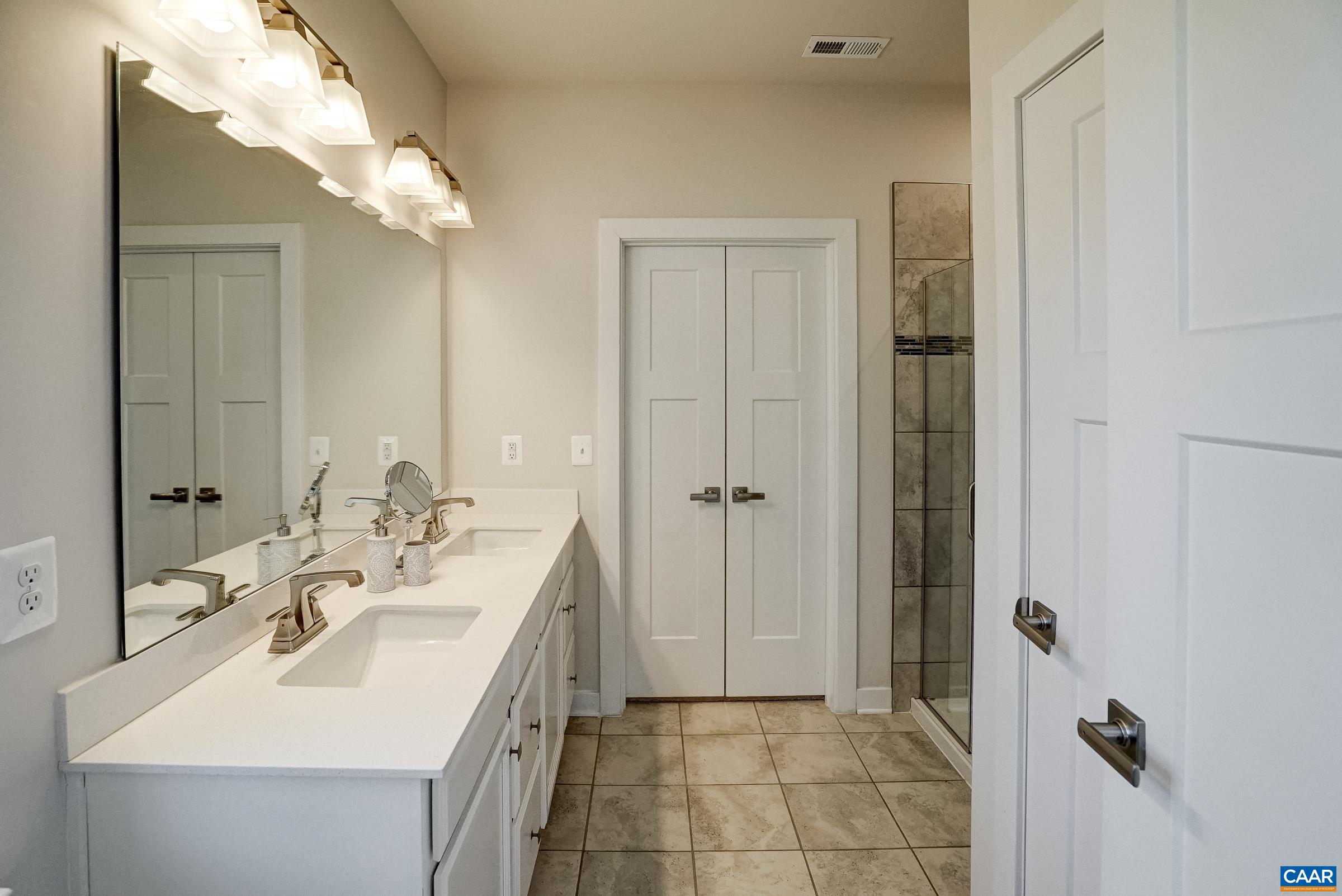Ensuite primary bathroom with linen closet, dual sink vanity, and walk-in shower. Ensuite primary bathroom with linen closet, dual sink vanity, and walk-in shower.