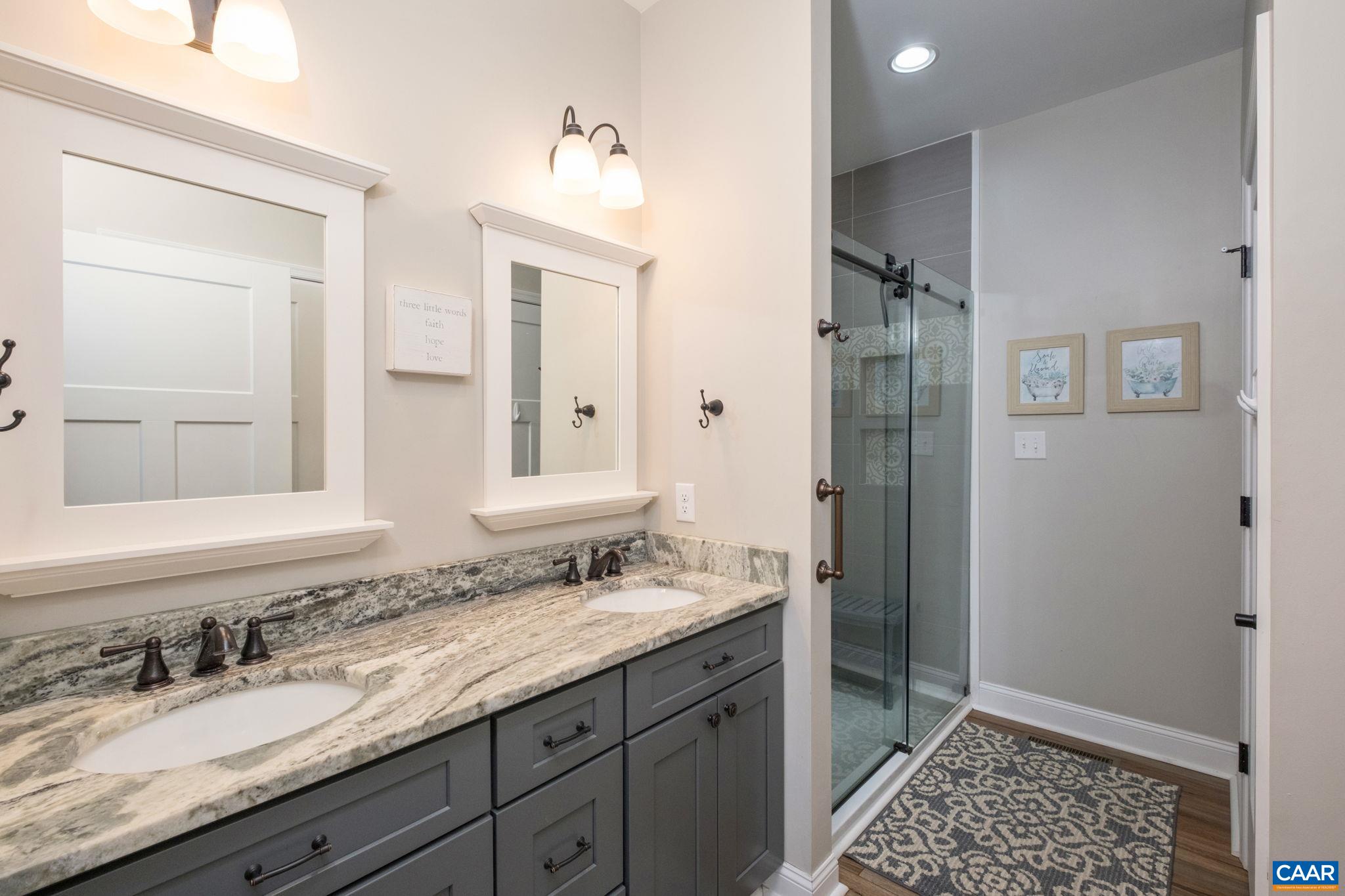 The primary bathroom features a glass-enclosed tiled shower, dual vanities, and a water closet. The primary bathroom features a glass-enclosed tiled shower, dual vanities, and a water closet.