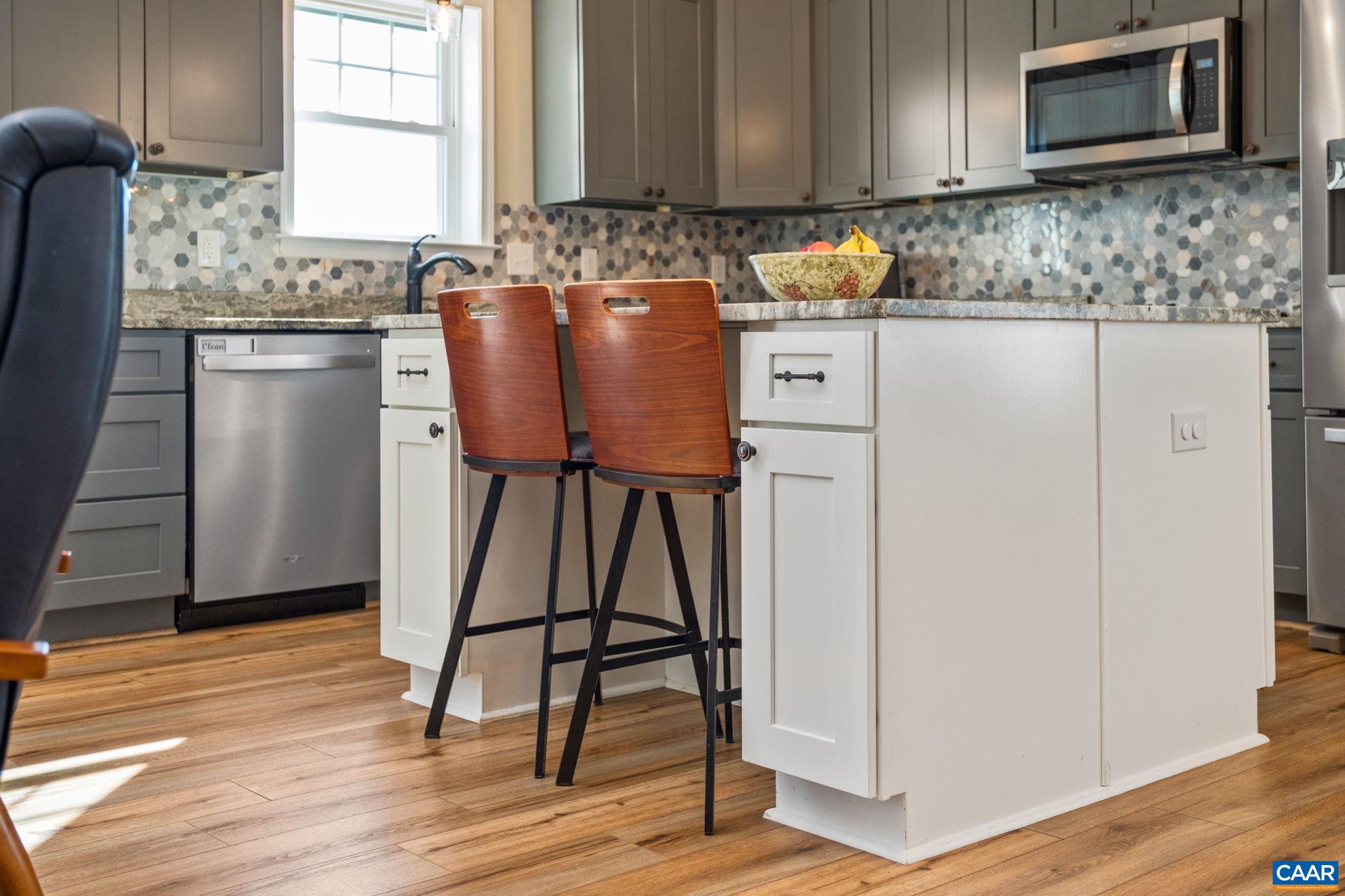 The island adds countertop space, a sitting area, and extra cabinetry for storage. The island adds countertop space, a sitting area, and extra cabinetry for storage.