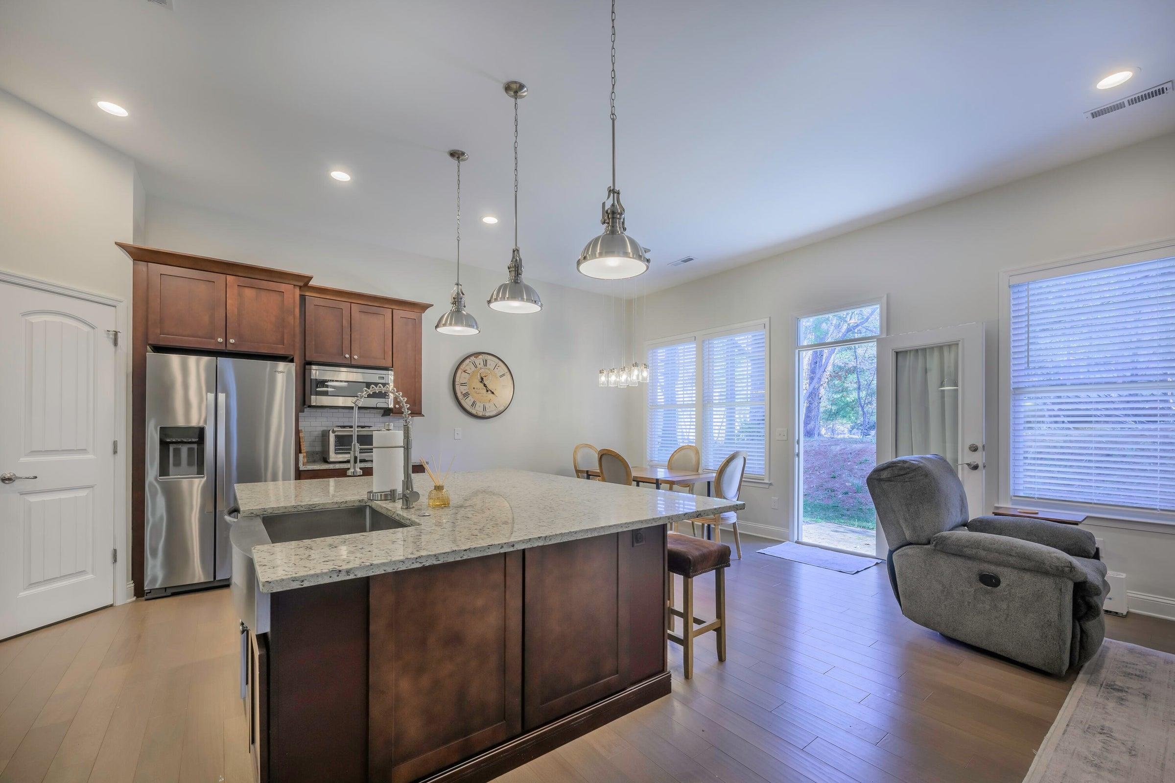 The kitchen boasts a 36” professional stainless steel range, granite countertops, a large center island, and a farmhouse sink.