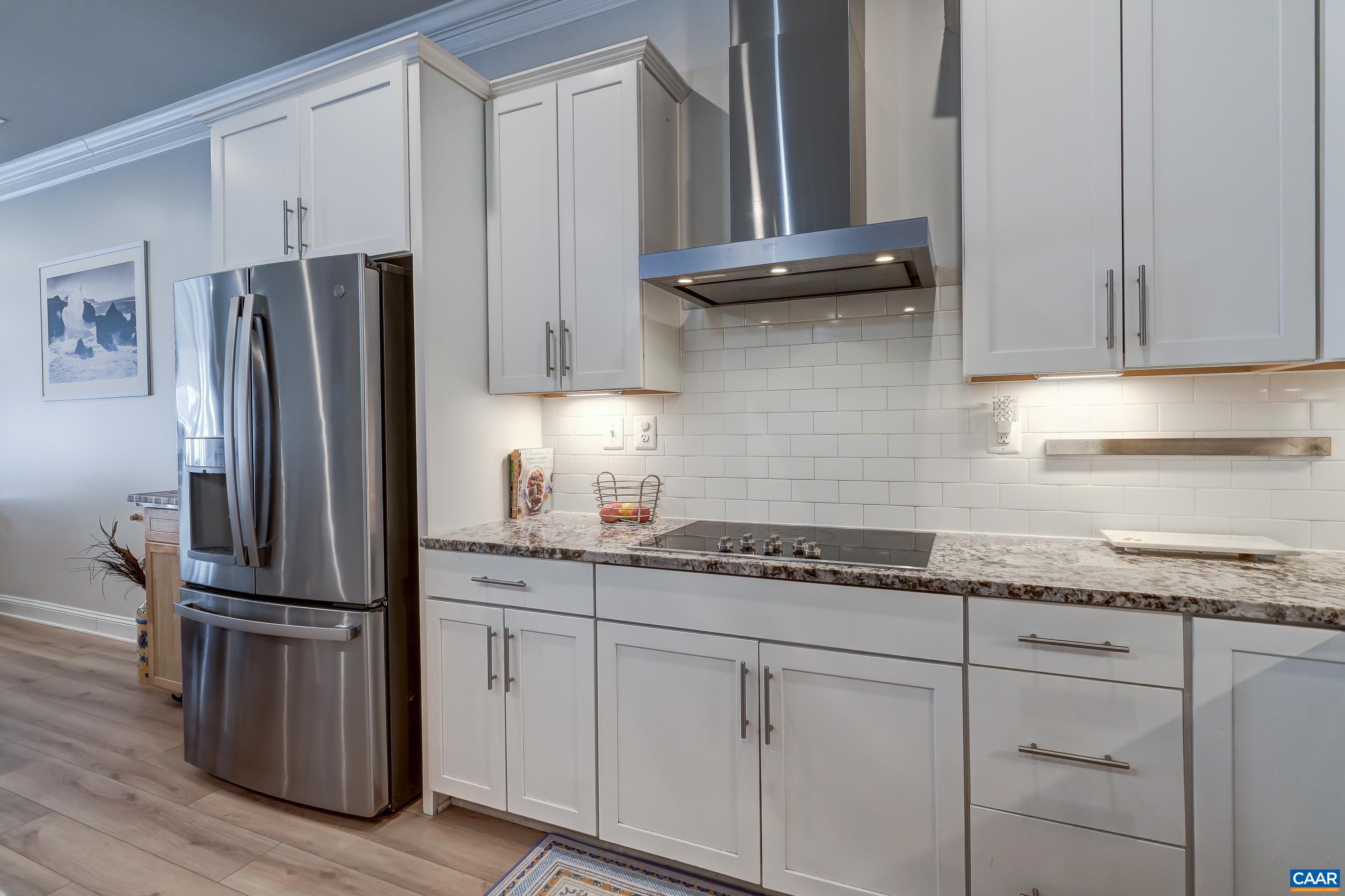 Gourmet kitchen with white cabinets, granite counters, subway tile backsplash and stainless appliances.