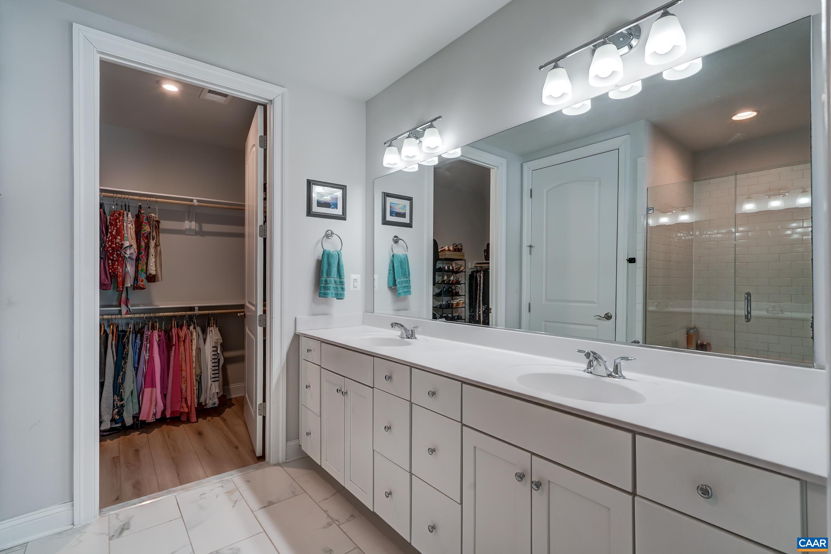 Primary bathroom features dual-sink vanity, and walk in shower.