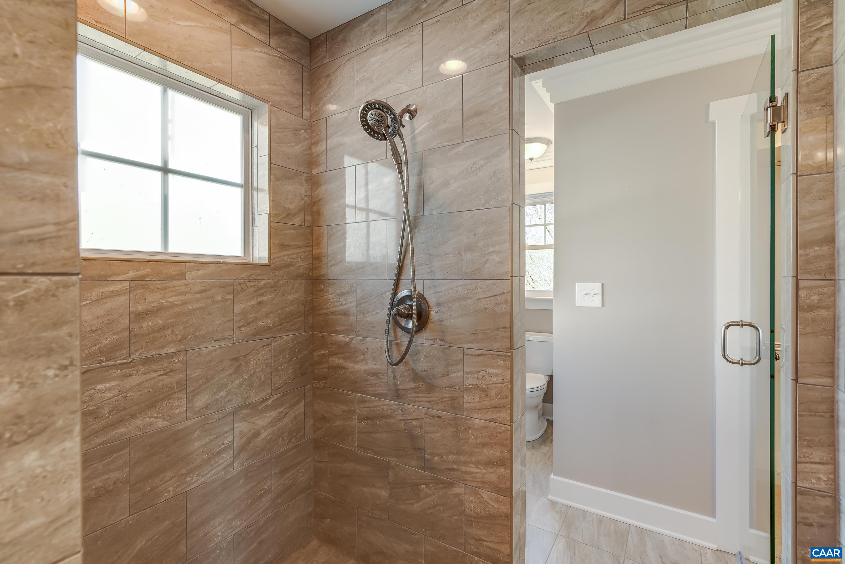 Pass through tiled shower with frameless glass doors.