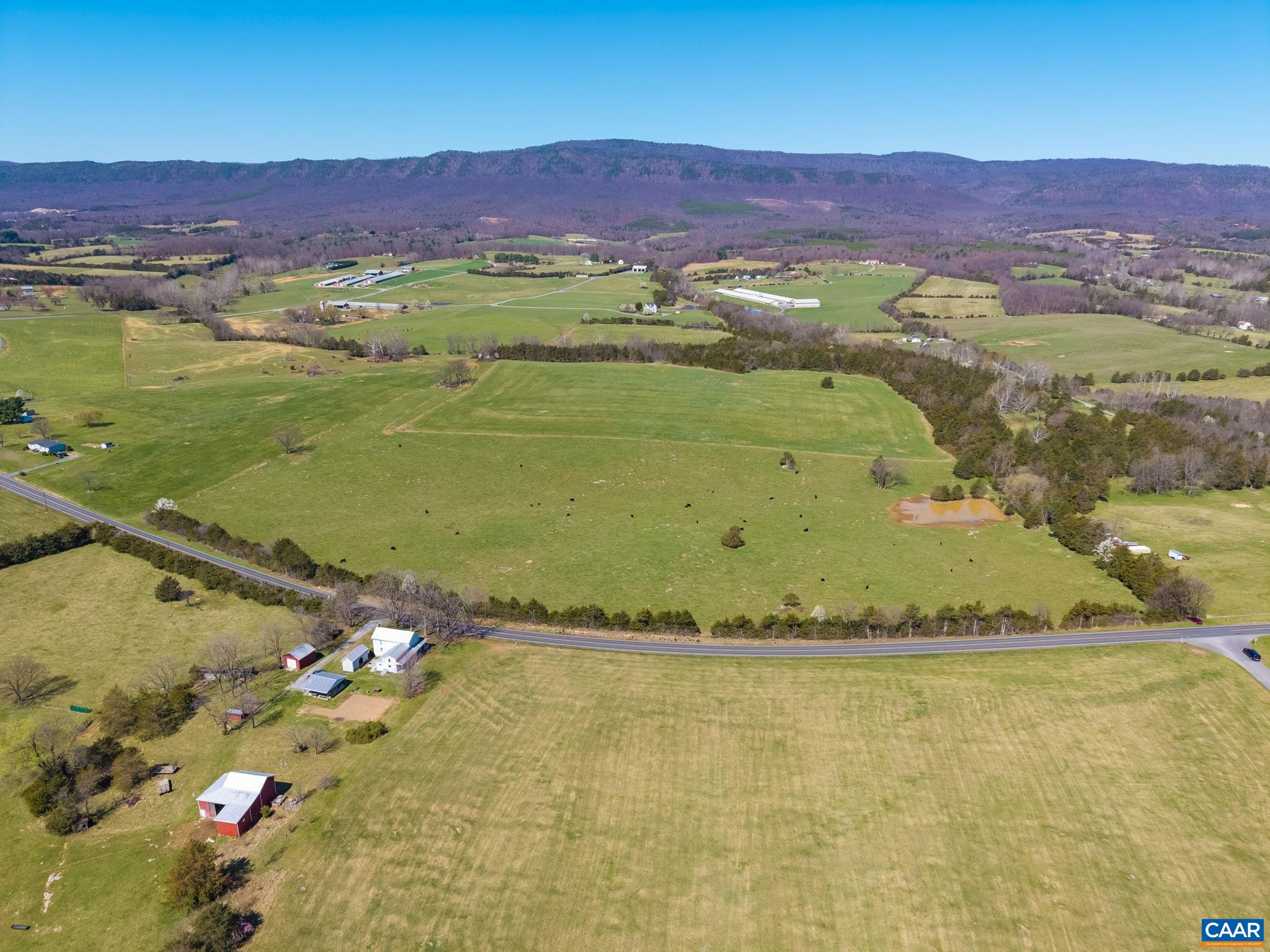 East Point Road frontage looking northwest.  In view is the grazing pasture with pond, and hay pasture just beyond.