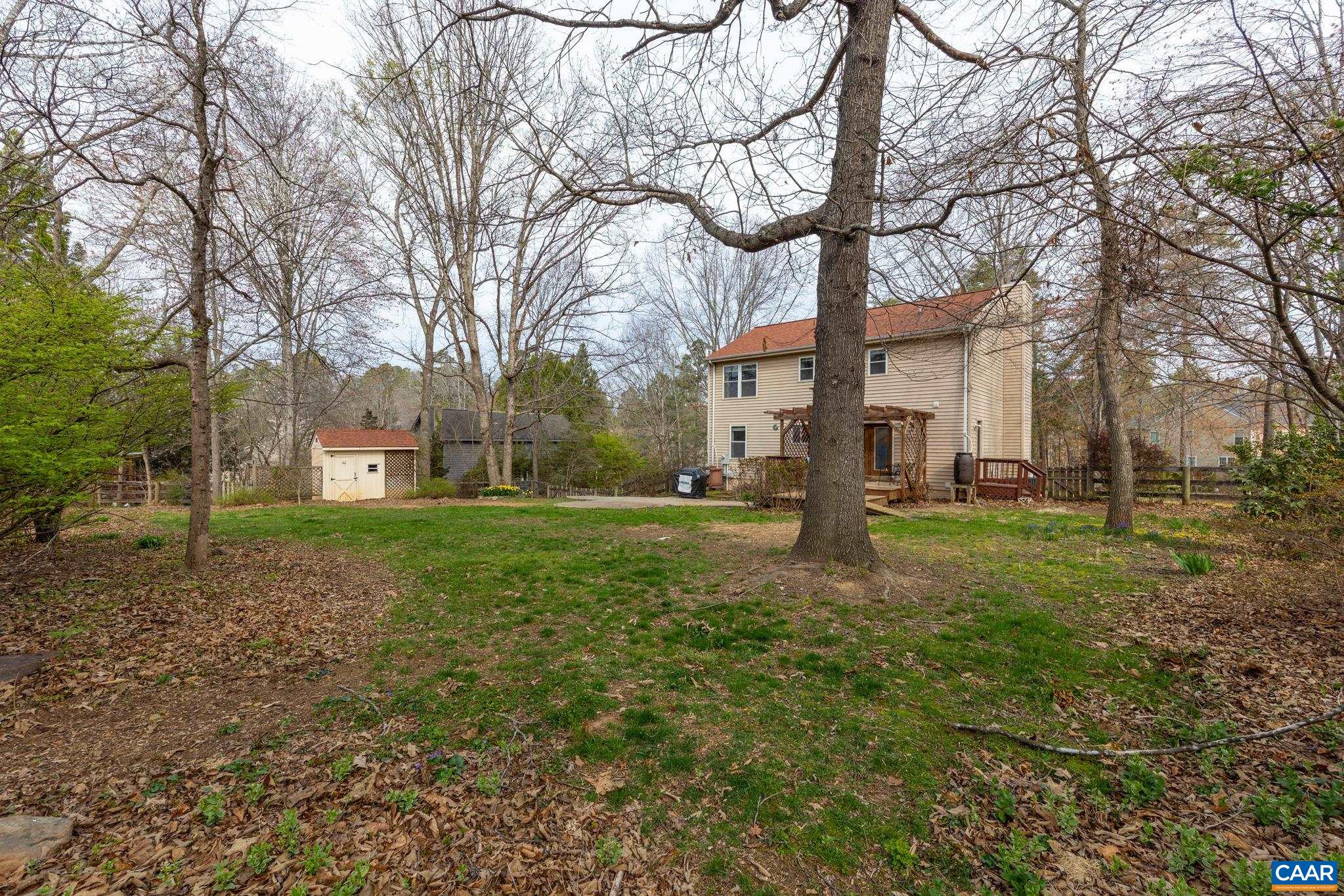 Large, fully fenced yard featuring a rear deck, patio, and a dedicated storage shed for tools and gear. Large, fully fenced yard featuring a rear deck, patio, and a dedicated storage shed for tools and gear.