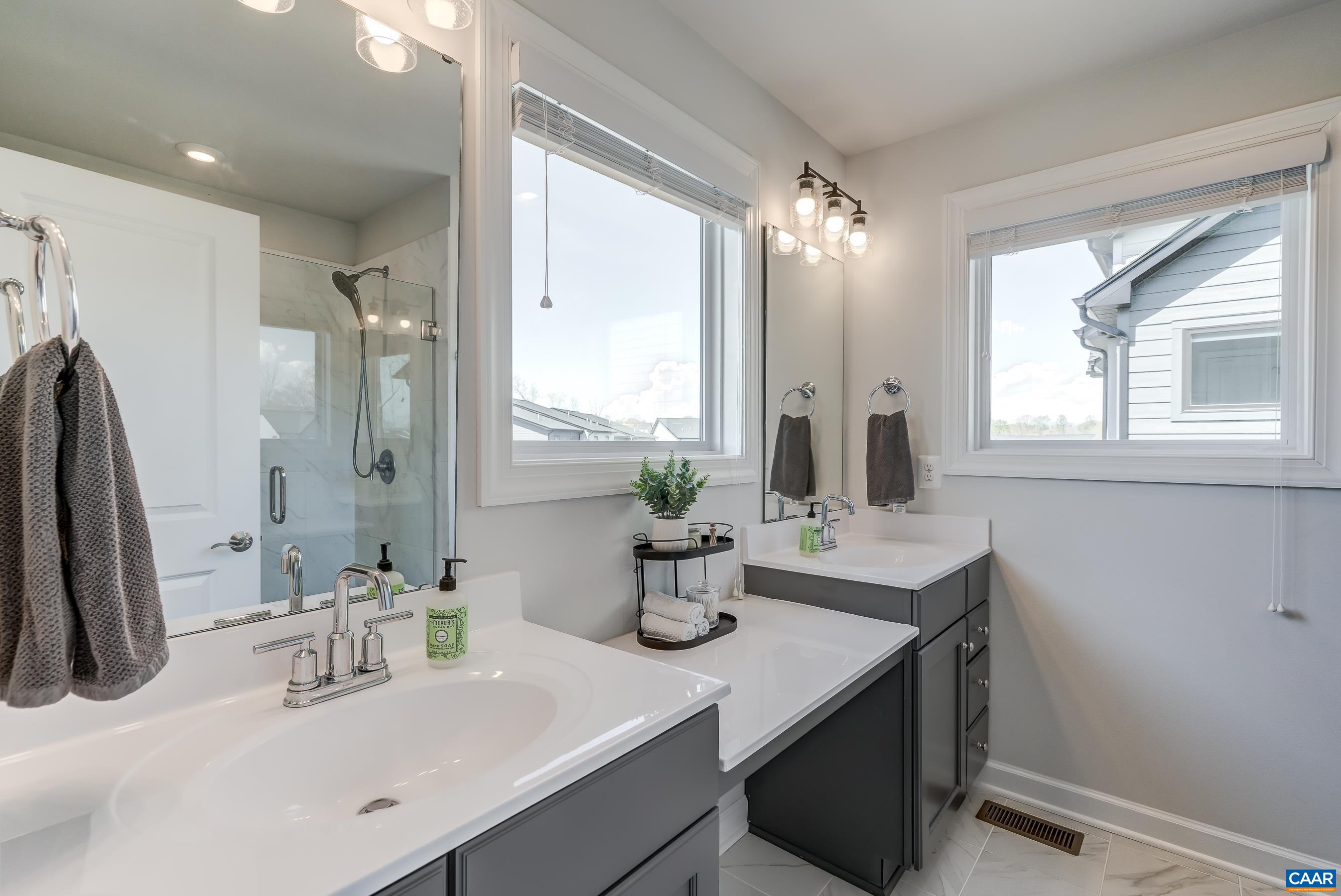 Primary bathroom features two separate vanities and a seating area.