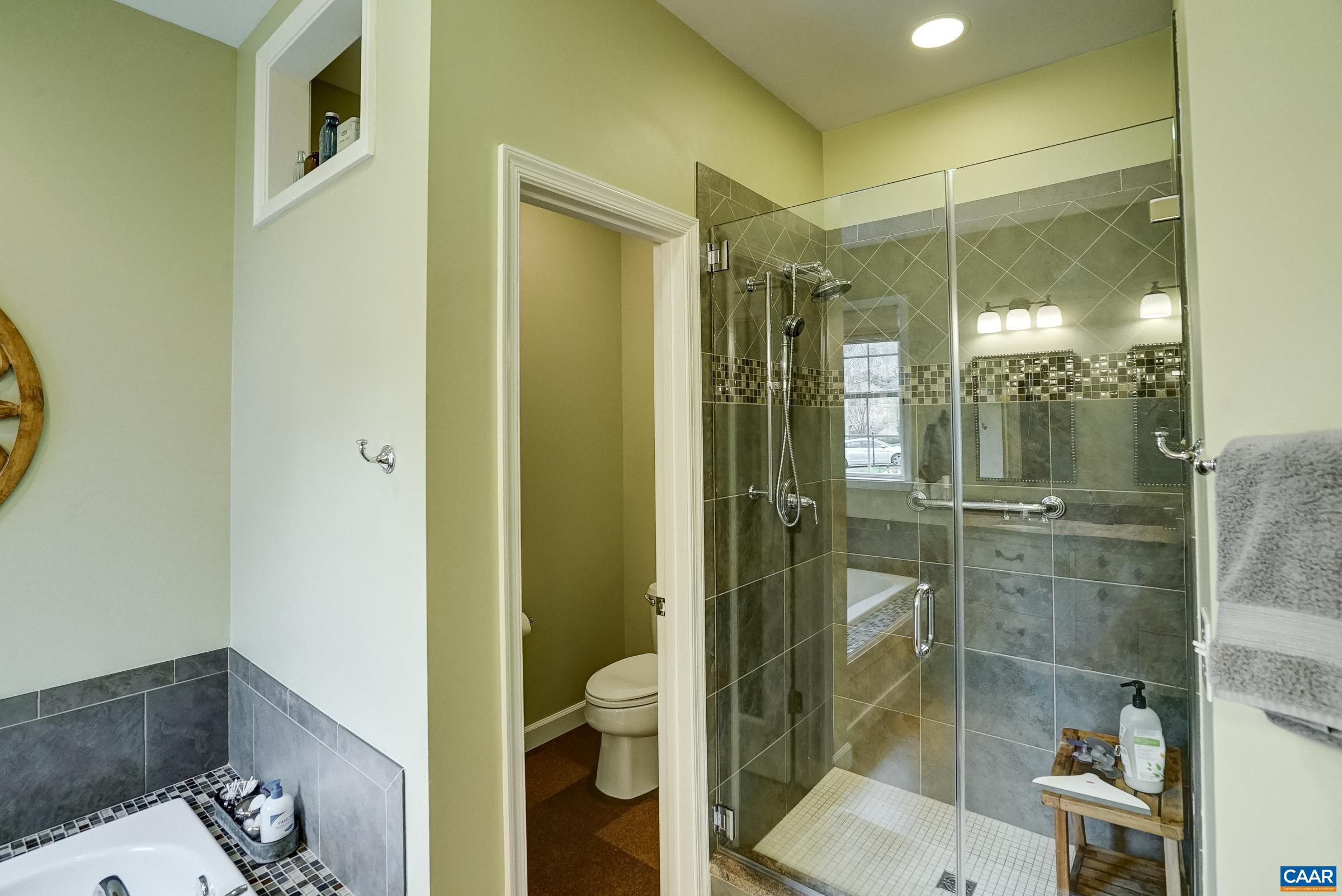 Frameless glass shower with hand-held sprayer.