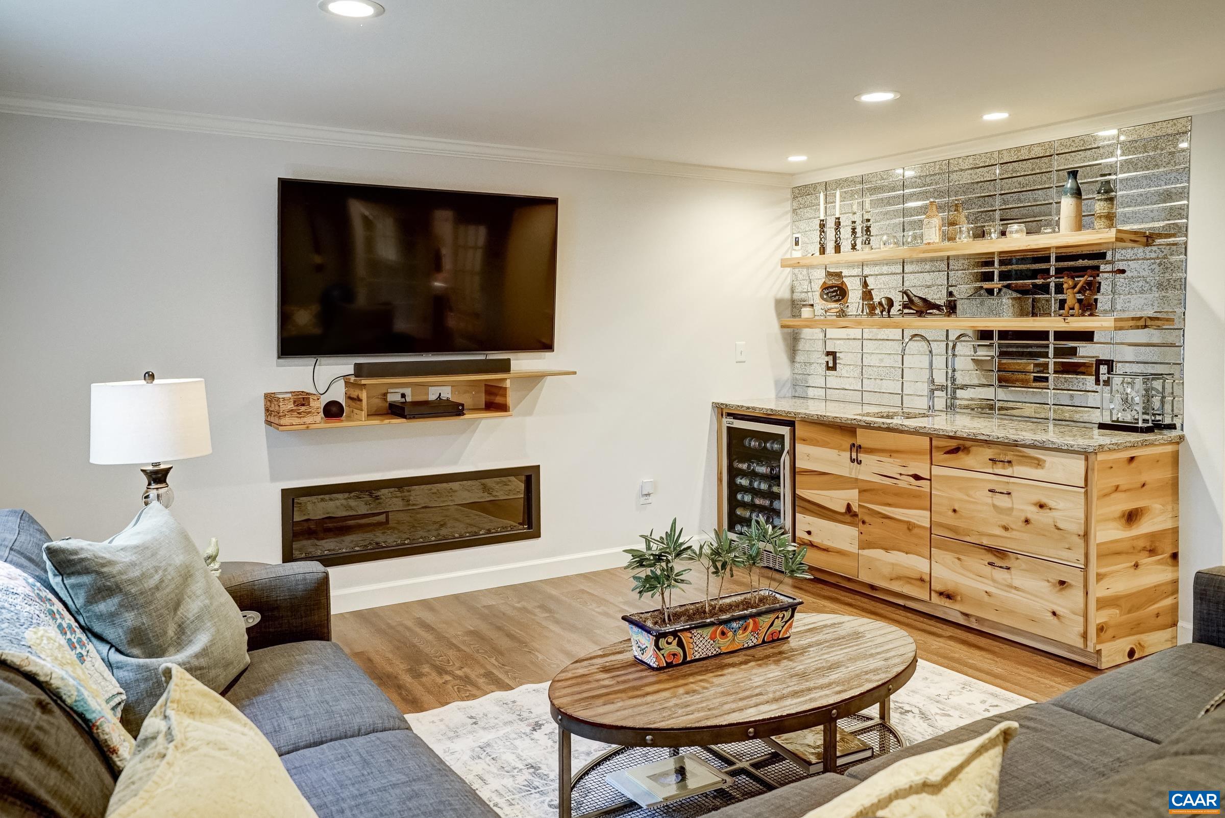 Rec room boasts a custom-built wet bar with beverage cooler, reclaimed poplar cabinets open live-edge shelves and a mirrored backsplash.