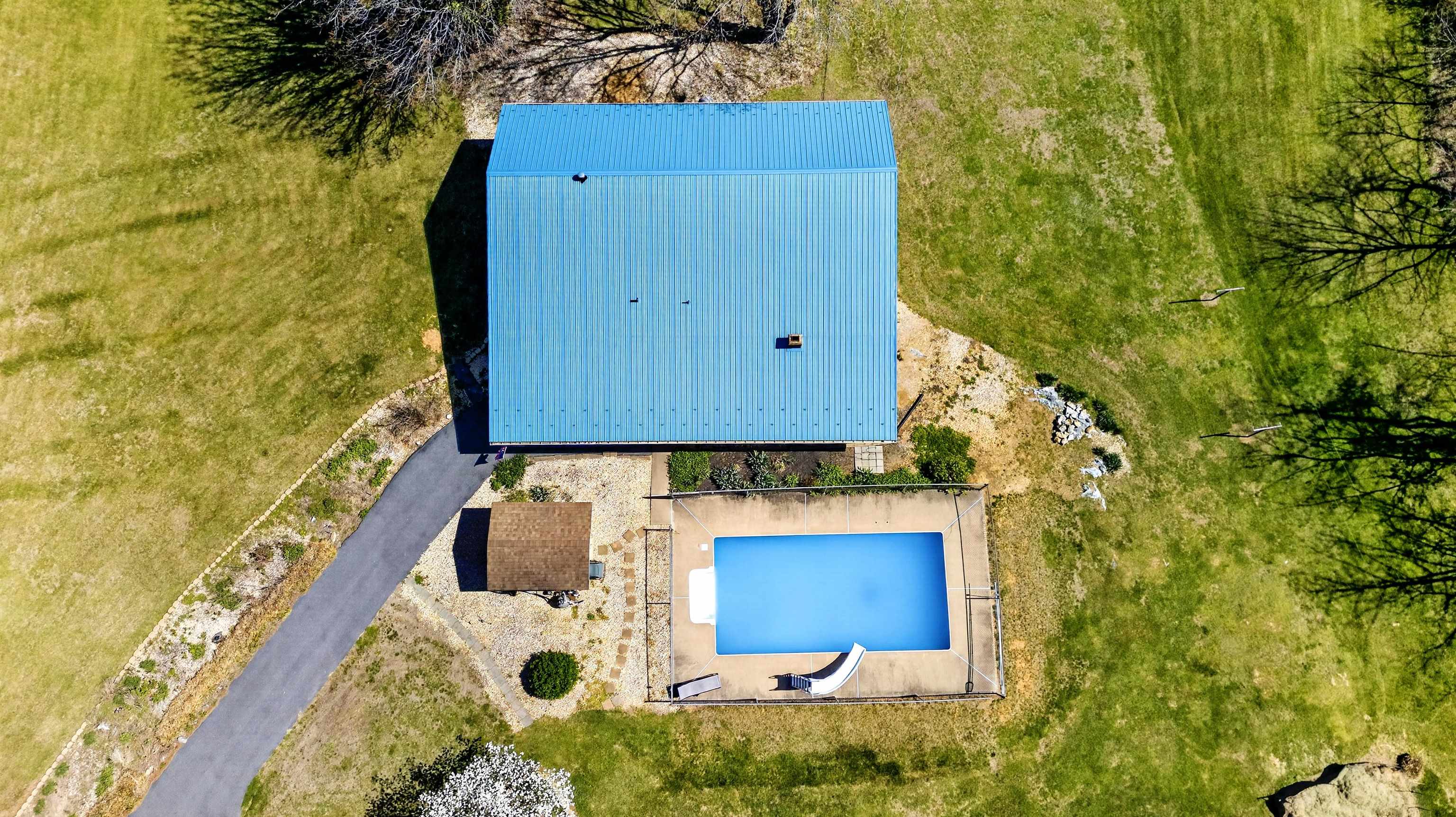 Aerial view highlighting the home, pool, and surrounding acreage, showcasing the layout, usable space, and peaceful setting.