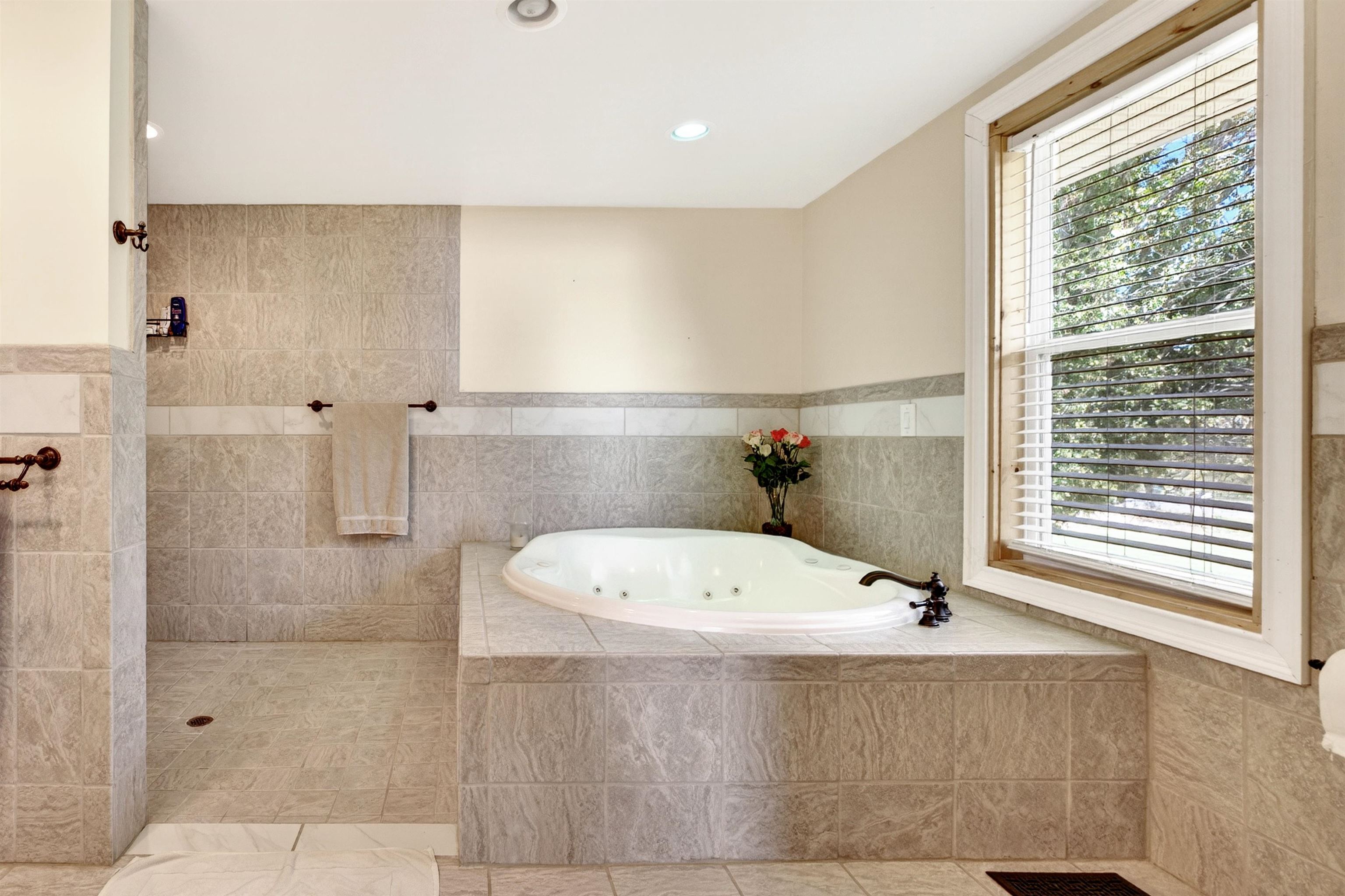 Spacious primary bath (approx. 13.3' x 11.9') featuring a tiled walk-in shower, oversized soaking/jetted tub, and room to comfortably move and unwind.