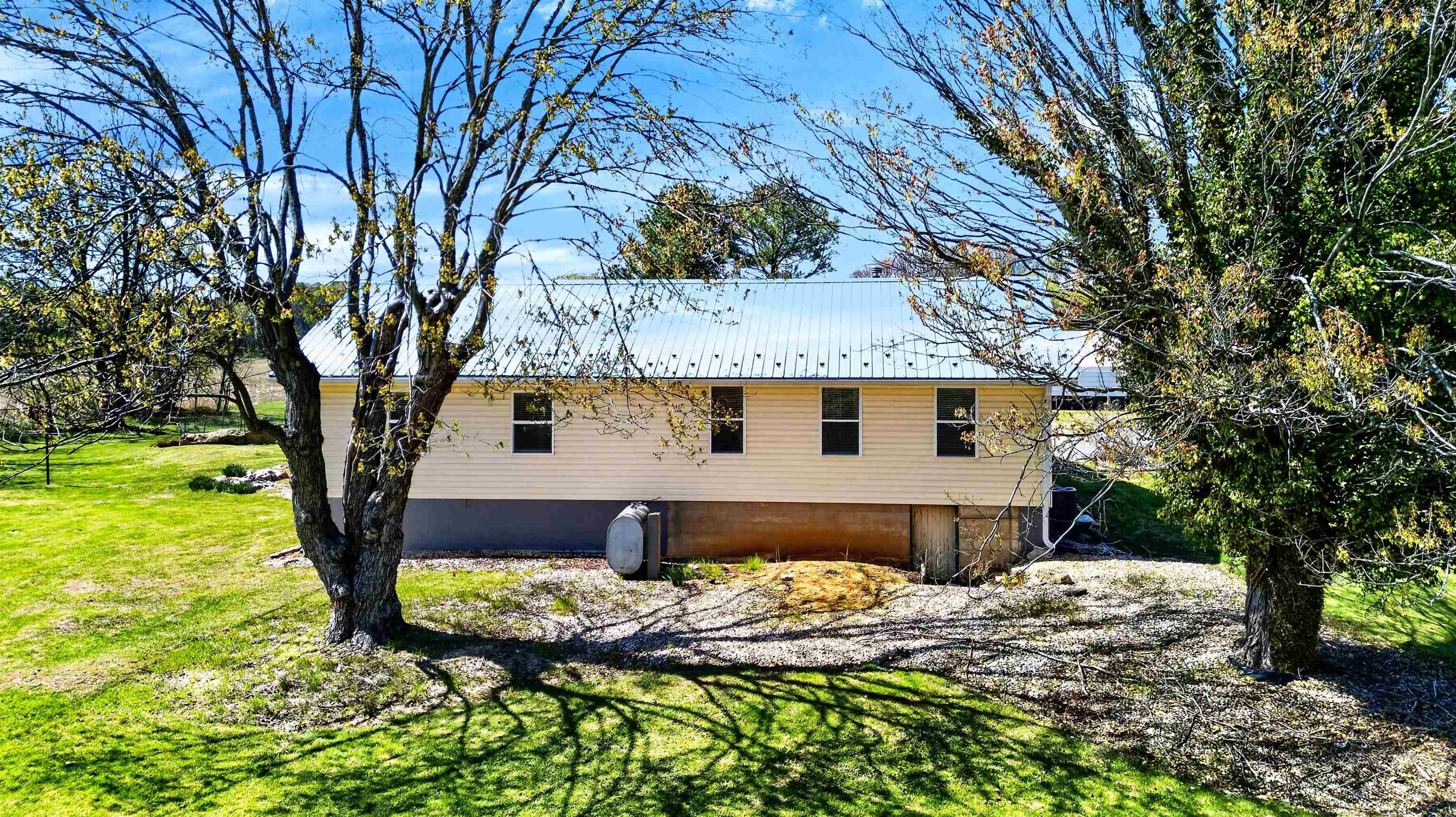 Charming view of the home set among mature trees, offering shade, privacy, and a peaceful outdoor setting.