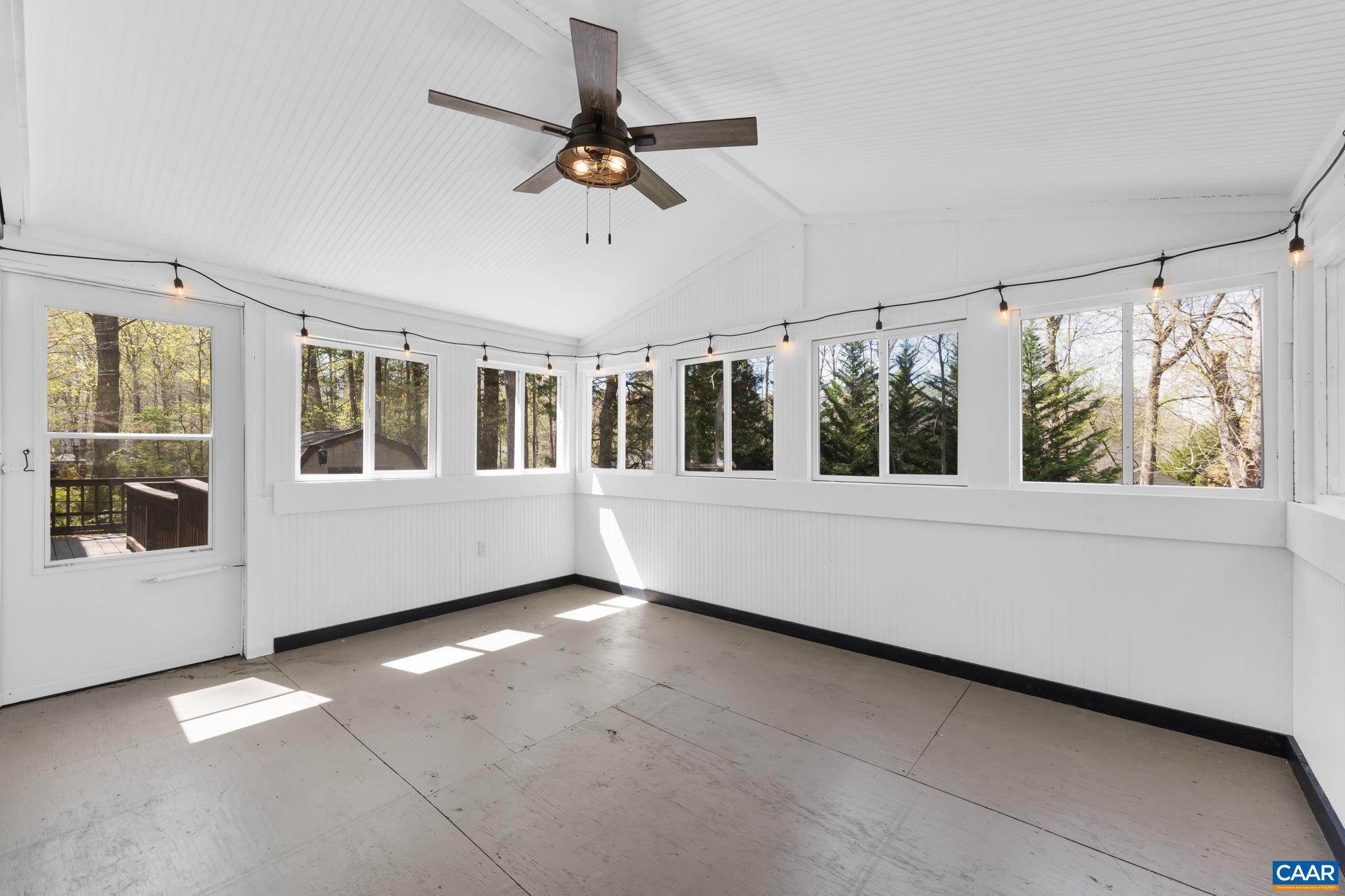 Enjoy the bright, spacious sunroom, perfectly lit by numerous windows and overhead string lights. This charming space features a ceiling fan for comfort and provides seamless access to the inviting rear deck—ideal for relaxing or entertaining! Enjoy the bright, spacious sunroom, perfectly lit by numerous windows and overhead string lights. This charming space features a ceiling fan for comfort and provides seamless access to the inviting rear deck—ideal for relaxing or entertaining!