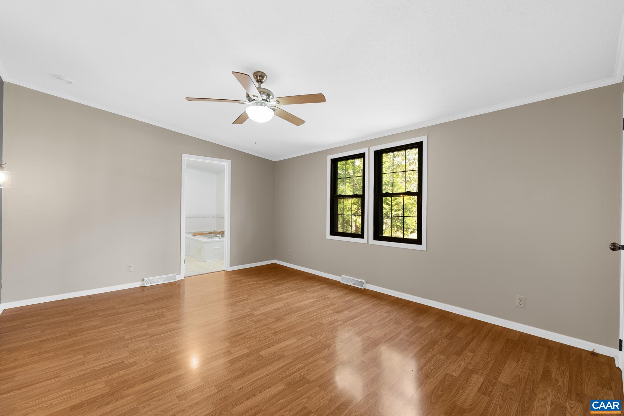 Spacious primary suite features hardwood-style flooring, a ceiling fan, and a private passage leading directly to the ensuite full bathroom. Spacious primary suite features hardwood-style flooring, a ceiling fan, and a private passage leading directly to the ensuite full bathroom.