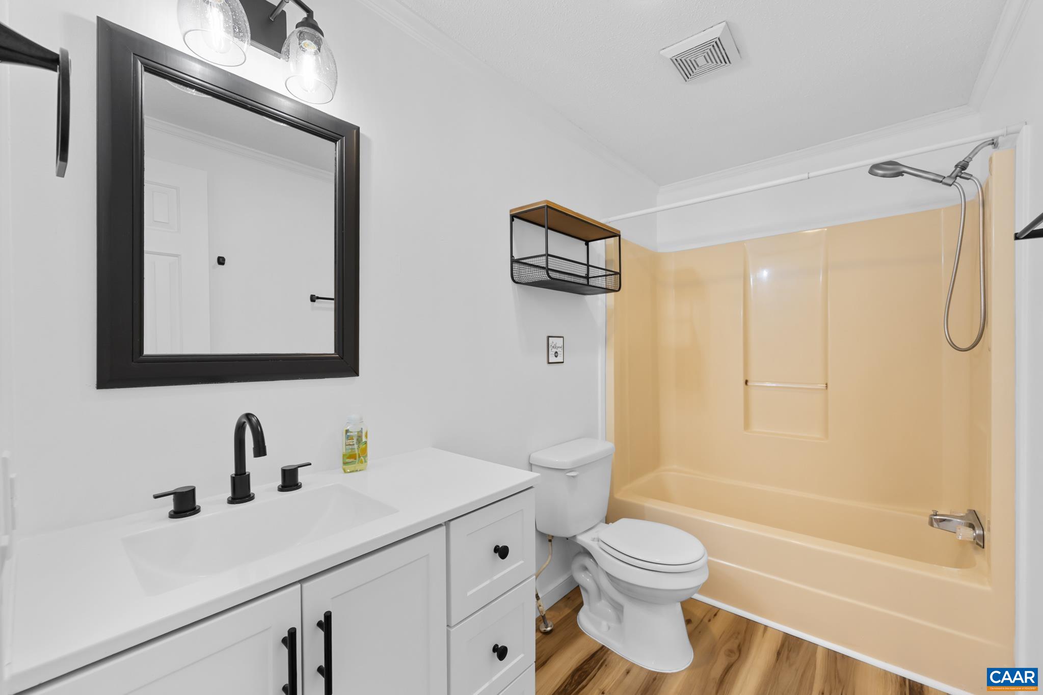 Step into this updated hall bath featuring a bright white vanity with a modern black faucet and hardware, set against a clean white wall. The functional tub/shower combo and wood-look flooring complete this fresh, move-in-ready space! Step into this updated hall bath featuring a bright white vanity with a modern black faucet and hardware, set against a clean white wall. The functional tub/shower combo and wood-look flooring complete this fresh, move-in-ready space!
