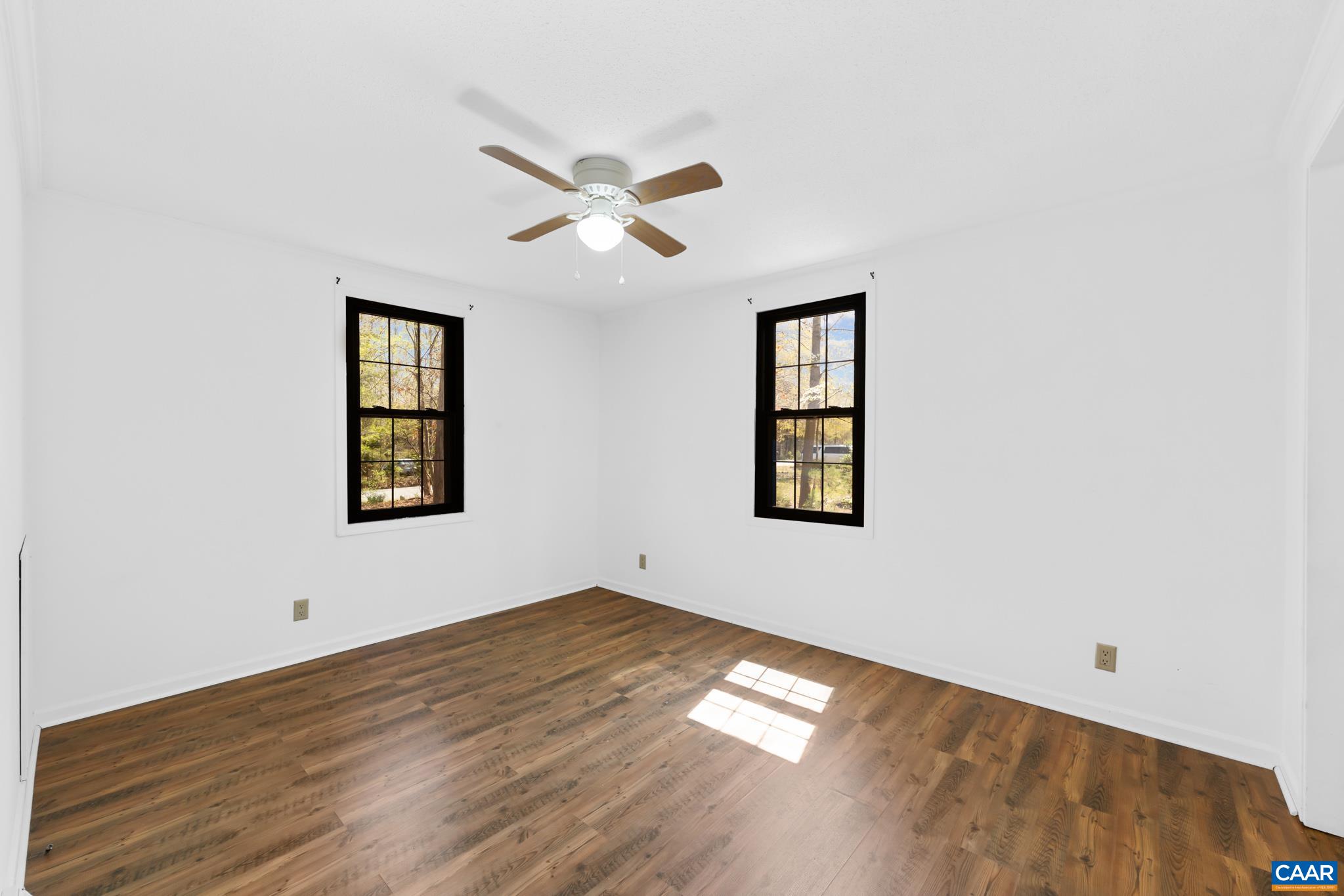 Bright and inviting, this third bedroom offers a fresh canvas for your personal style. Enjoy the modern wood-look floors, crisp white walls, and a ceiling fan for comfort. Large windows frame views and fill the room with light. Bright and inviting, this third bedroom offers a fresh canvas for your personal style. Enjoy the modern wood-look floors, crisp white walls, and a ceiling fan for comfort. Large windows frame views and fill the room with light.