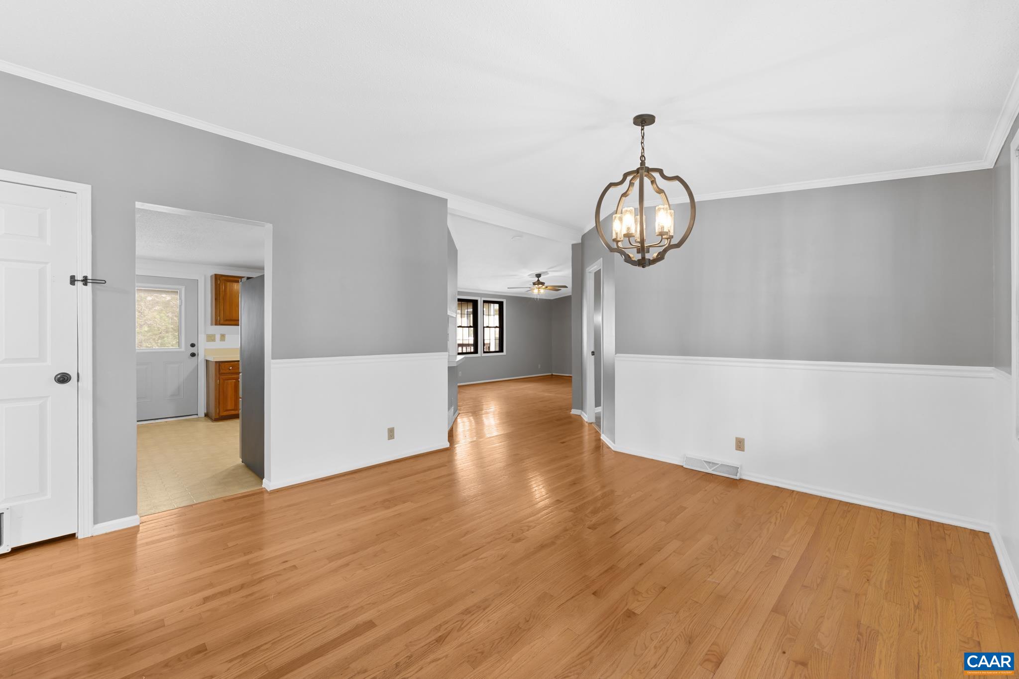 Bright, open-concept dining space featuring beautiful hardwood floors, modern wainscoting, and an elegant chandelier. Seamless flow to the kitchen and living area, perfect for entertaining! Bright, open-concept dining space featuring beautiful hardwood floors, modern wainscoting, and an elegant chandelier. Seamless flow to the kitchen and living area, perfect for entertaining!