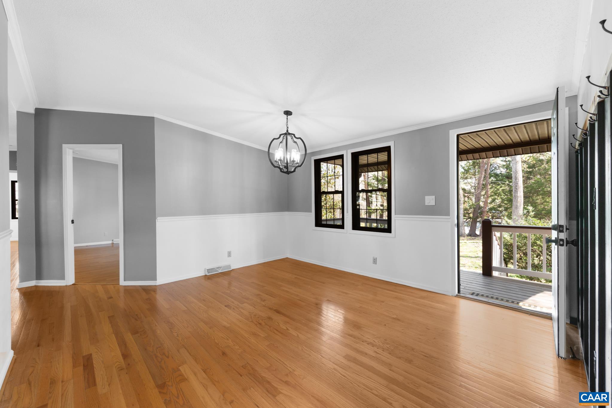 This bright and airy room features gleaming hardwood floors, stylish two-tone walls, and a distinctive black chandelier. Double windows and a glass door leading to a covered porch fill the space with natural light. Perfect for dining or entertaining! This bright and airy room features gleaming hardwood floors, stylish two-tone walls, and a distinctive black chandelier. Double windows and a glass door leading to a covered porch fill the space with natural light. Perfect for dining or entertaining!