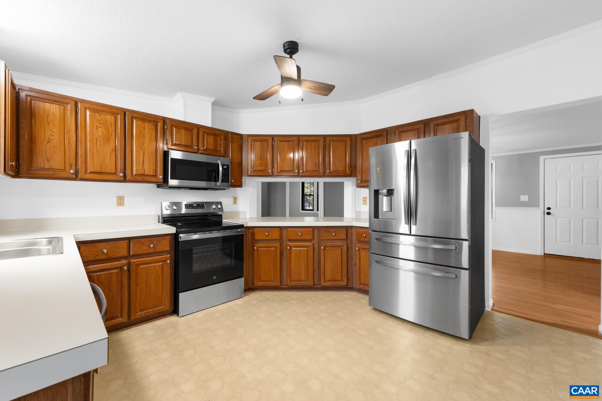 Enjoy this bright kitchen featuring ample wood cabinetry, expansive white countertops, and modern stainless steel appliances, including a spacious French door refrigerator, microwave, and range. Enjoy this bright kitchen featuring ample wood cabinetry, expansive white countertops, and modern stainless steel appliances, including a spacious French door refrigerator, microwave, and range.