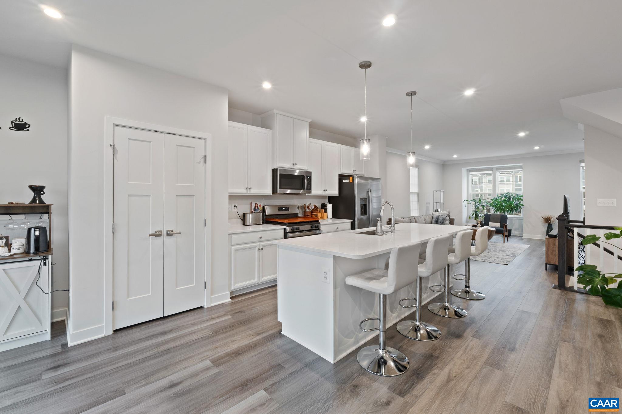 Bright, open-concept kitchen showcasing a spacious island with seating, white cabinetry, stainless steel appliances, and seamless flow into the living area—perfect for entertaining. Bright, open-concept kitchen showcasing a spacious island with seating, white cabinetry, stainless steel appliances, and seamless flow into the living area—perfect for entertaining.