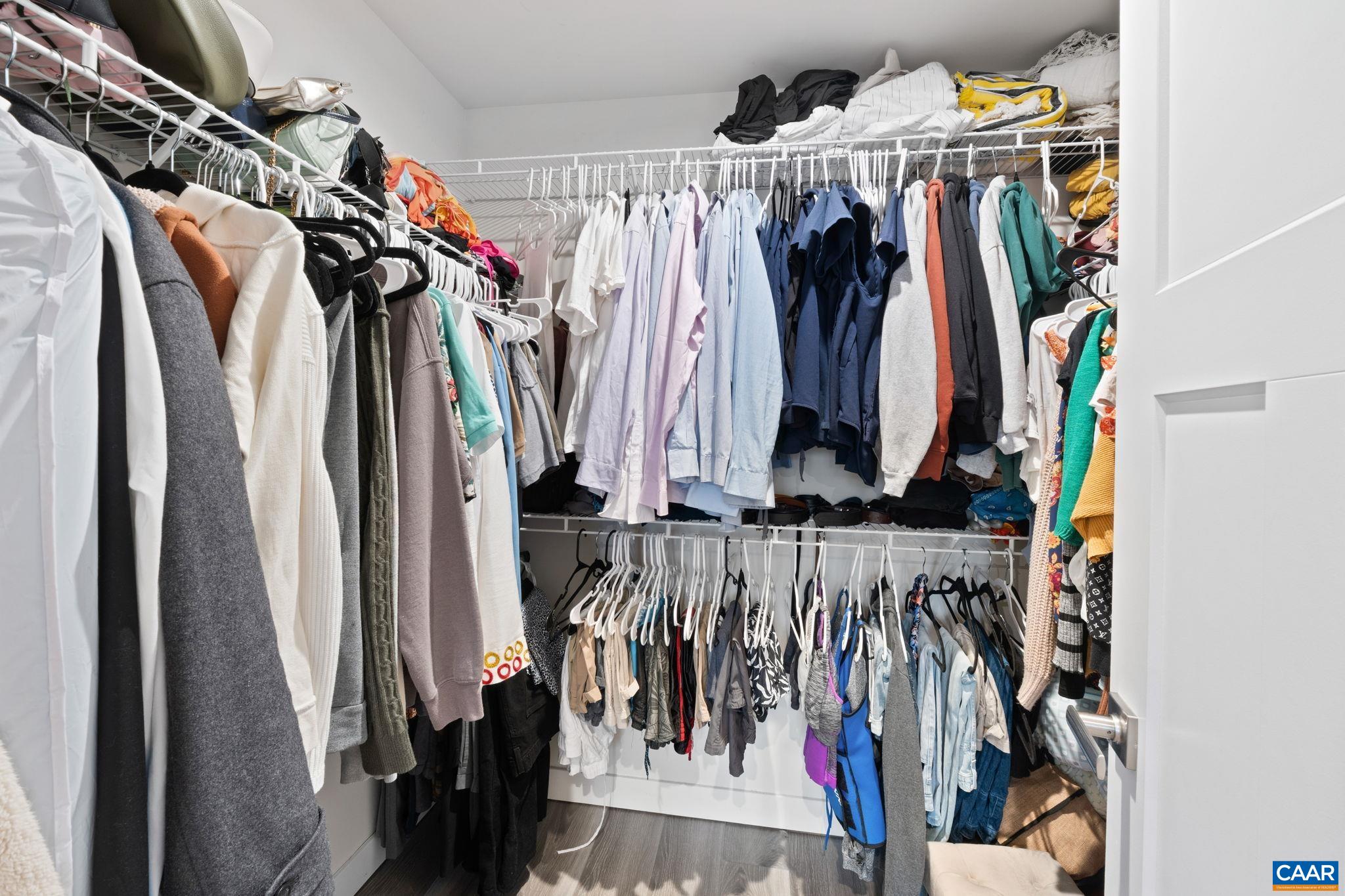 Spacious walk-in closet with built-in shelving and double hanging rods, offering ample storage and organization. Spacious walk-in closet with built-in shelving and double hanging rods, offering ample storage and organization.