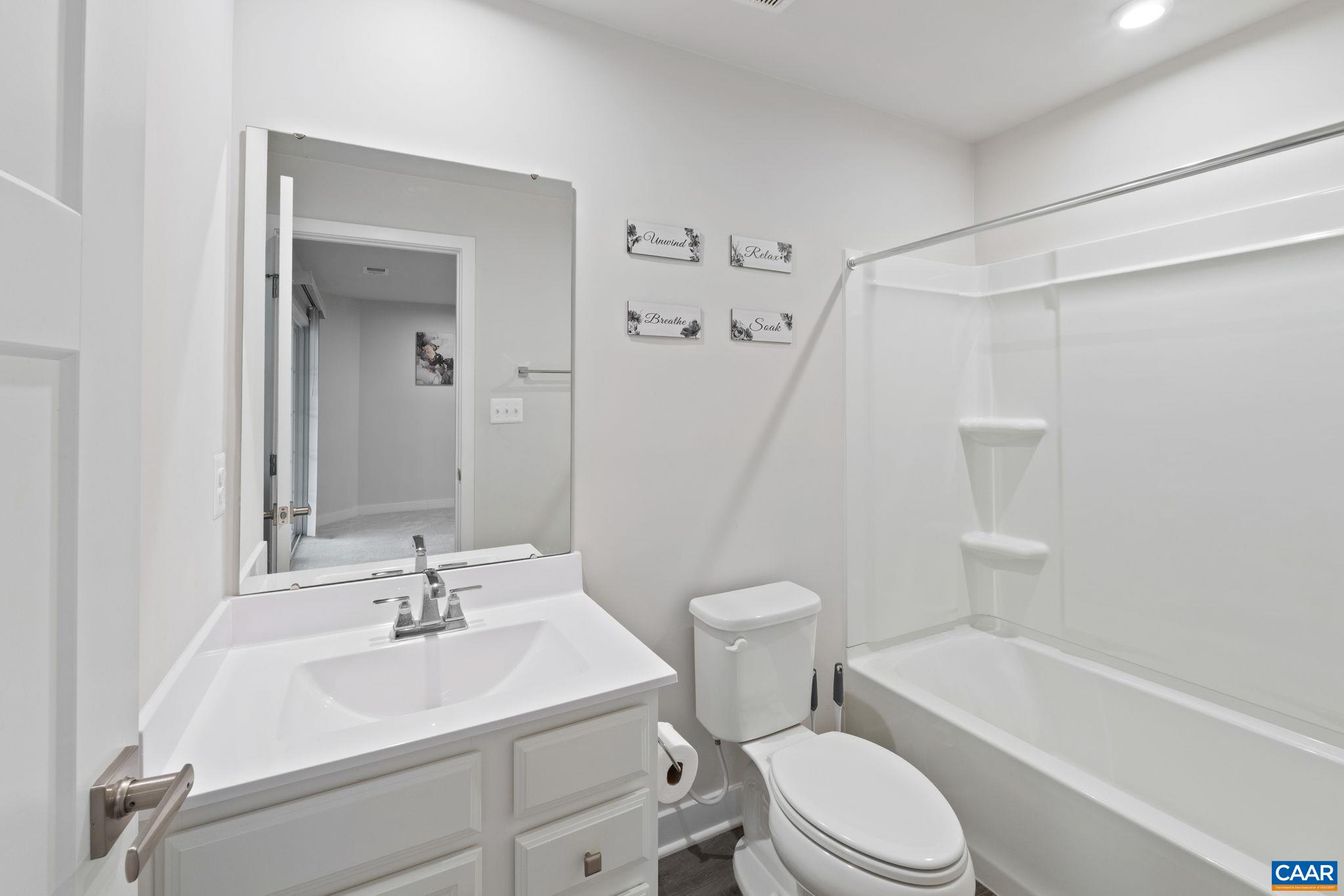 Full bathroom featuring single vanity, tub/shower combination, and clean, modern finishes. Full bathroom featuring single vanity, tub/shower combination, and clean, modern finishes.