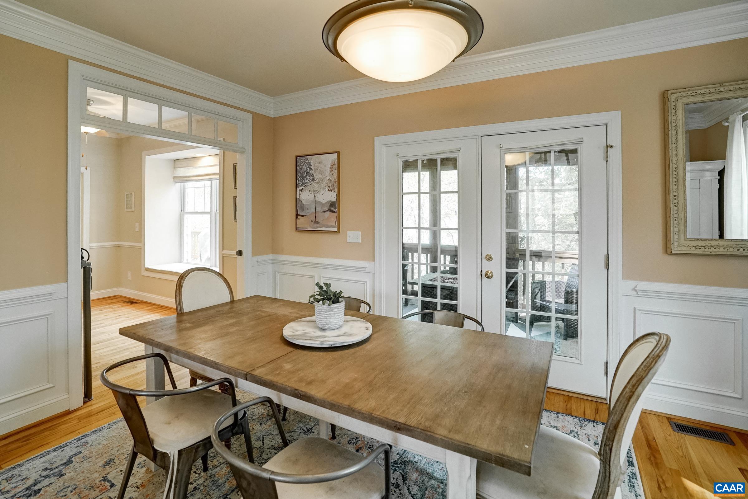 Formal dining room features wainscoting trim and French doors leading to screened porch.