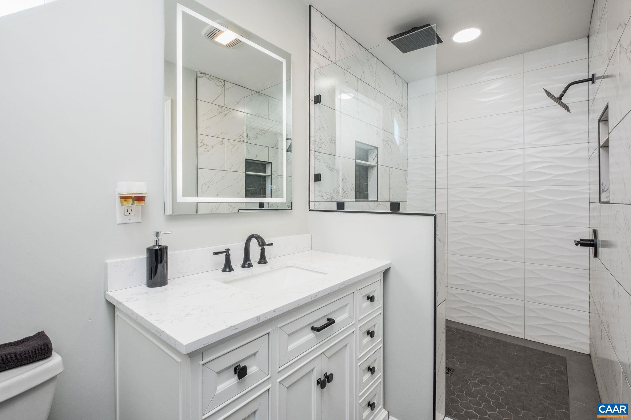 Completely renovated primary bathroom with large walk in shower featuring double shower heads and rain heads.