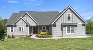 Manicured Landscaping, Hardiboard Siding and Concrete walkway to Paved Driveway