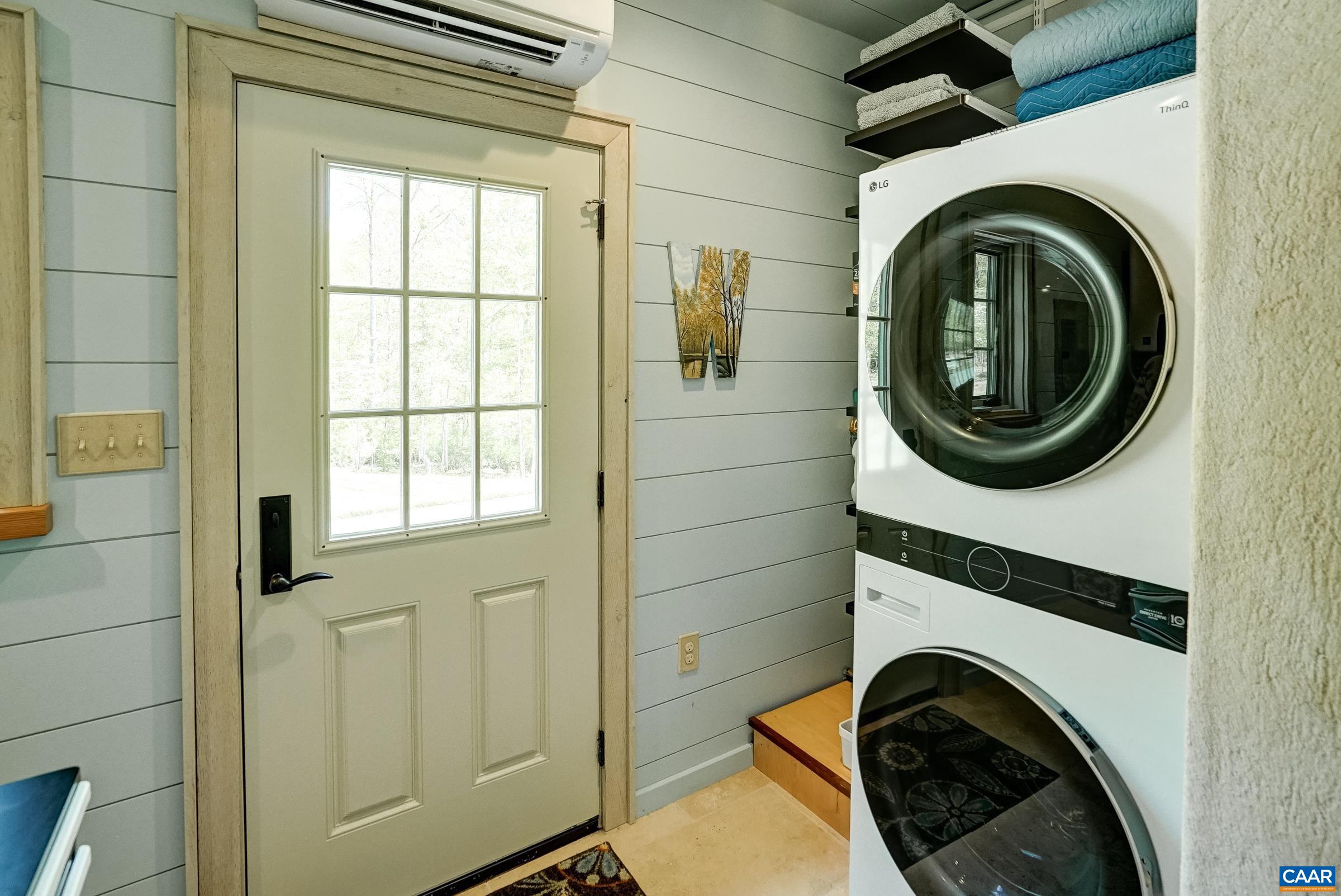 Laundry room in guest house features a stacked  LG washer and dryer with folding area.