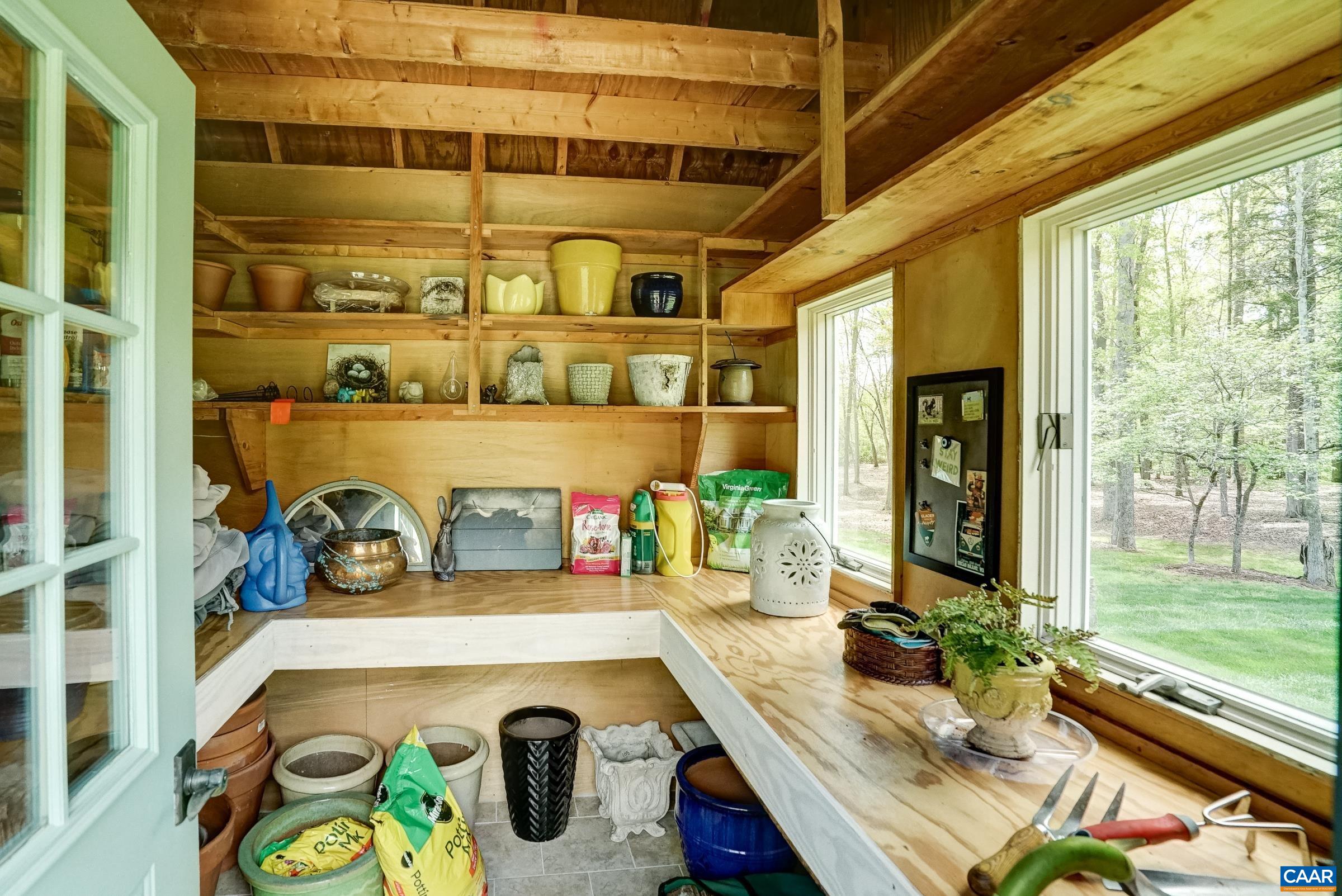 Light filled potting shed features workbench and shelves.