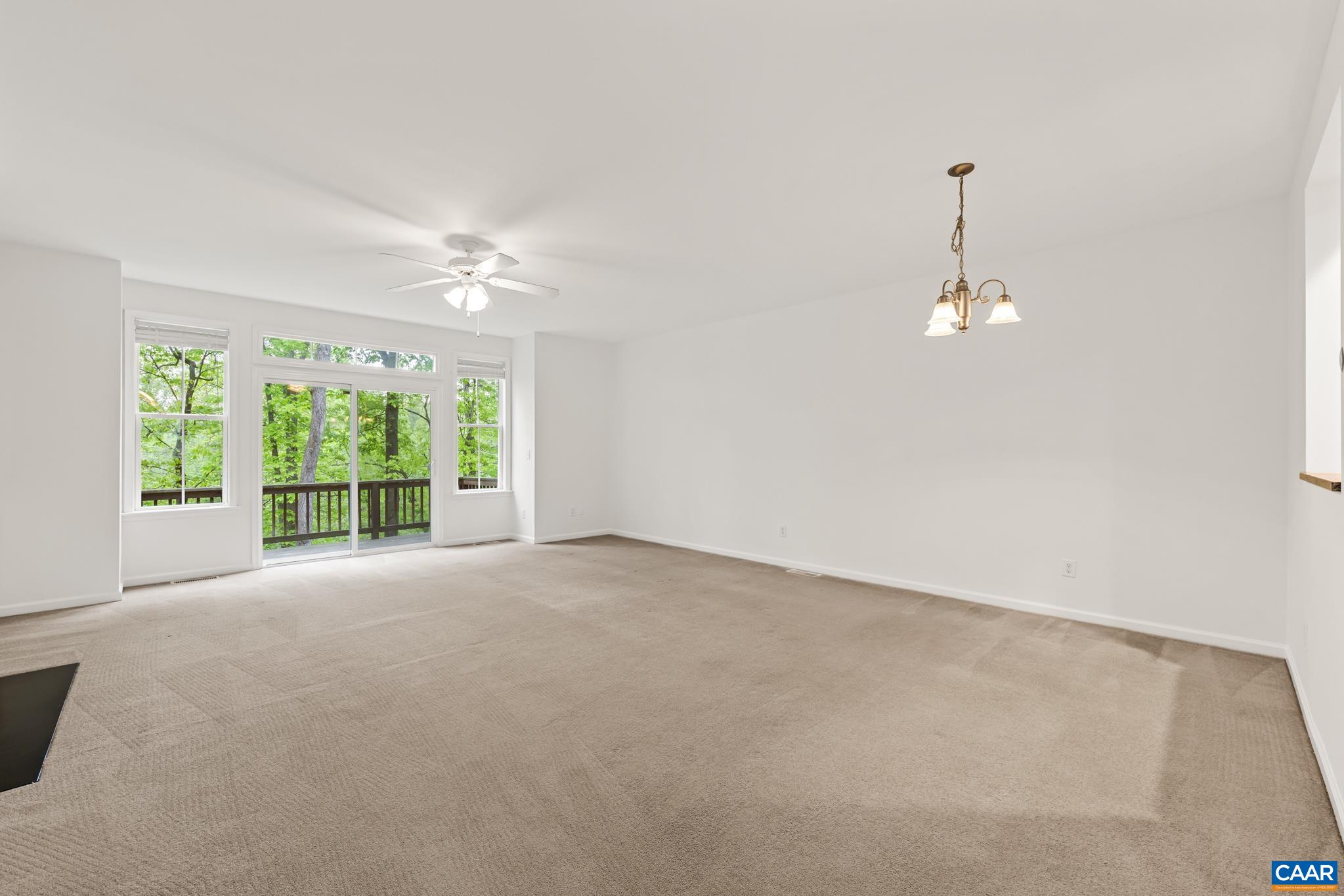 Large living room with gas fireplace and views of the woods off the deck.
