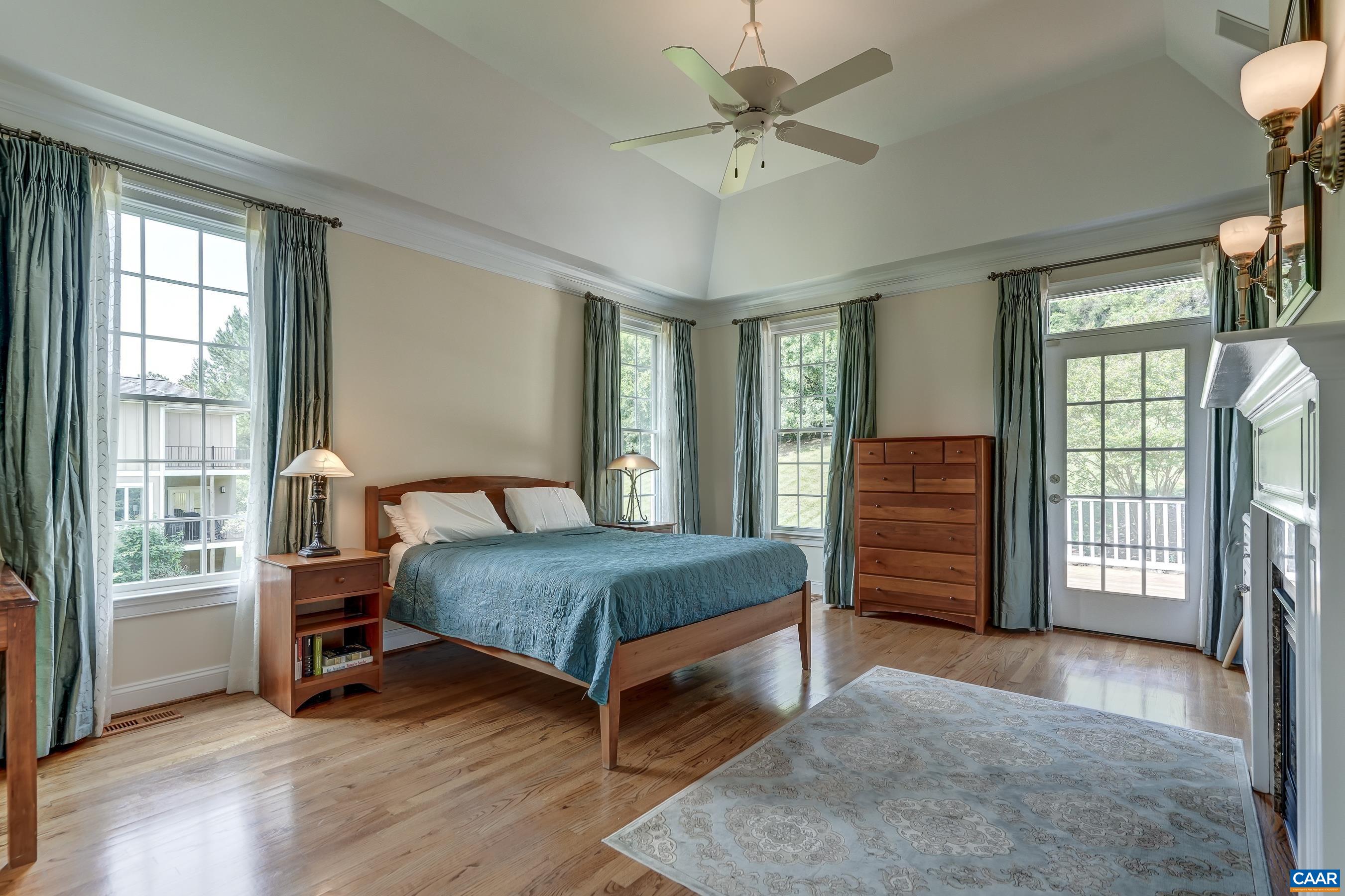 Primary suite features hardwood floors, high ceiling, fan, and fireplace with built-ins.