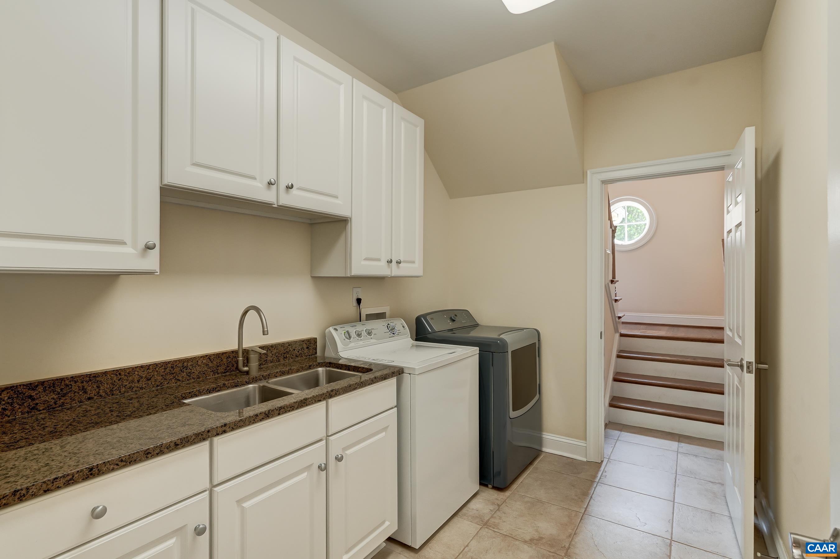 Main level laundry room features extra cabinets, and access to the back stairs.