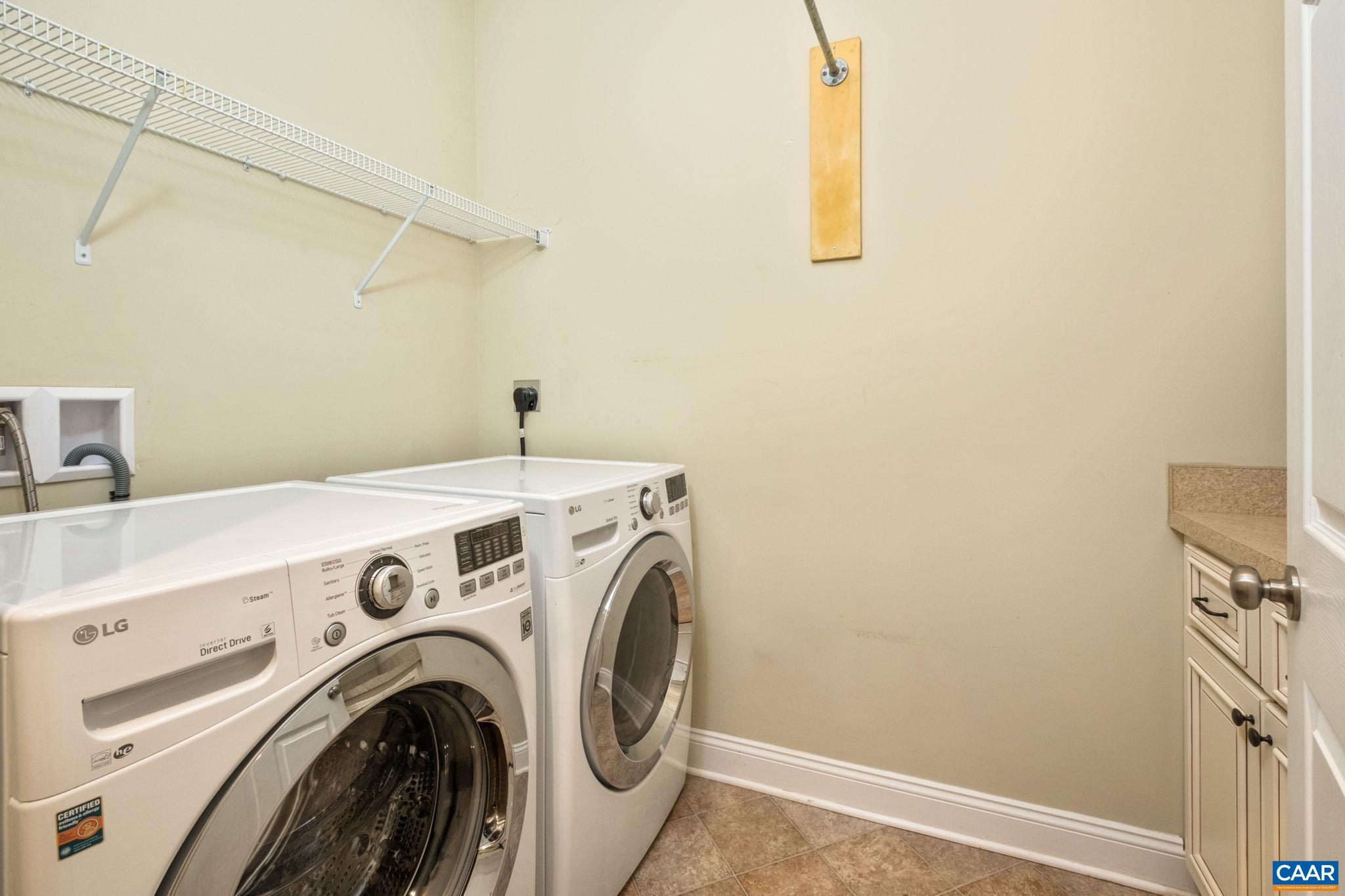 Large laundry room with LG washer and dryer, and storage cabinets.