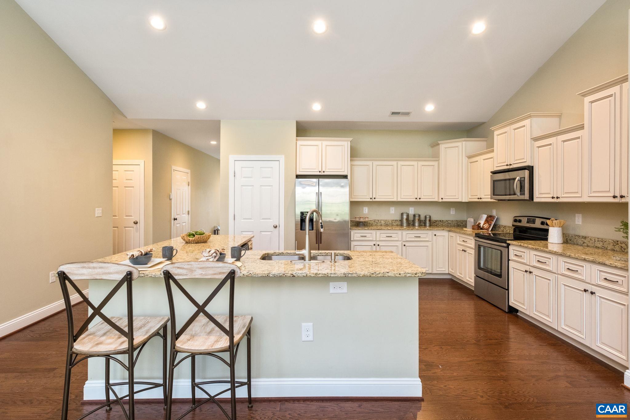 Luxury kitchen features an oversized L shaped island, granite countertops and white cabinets.