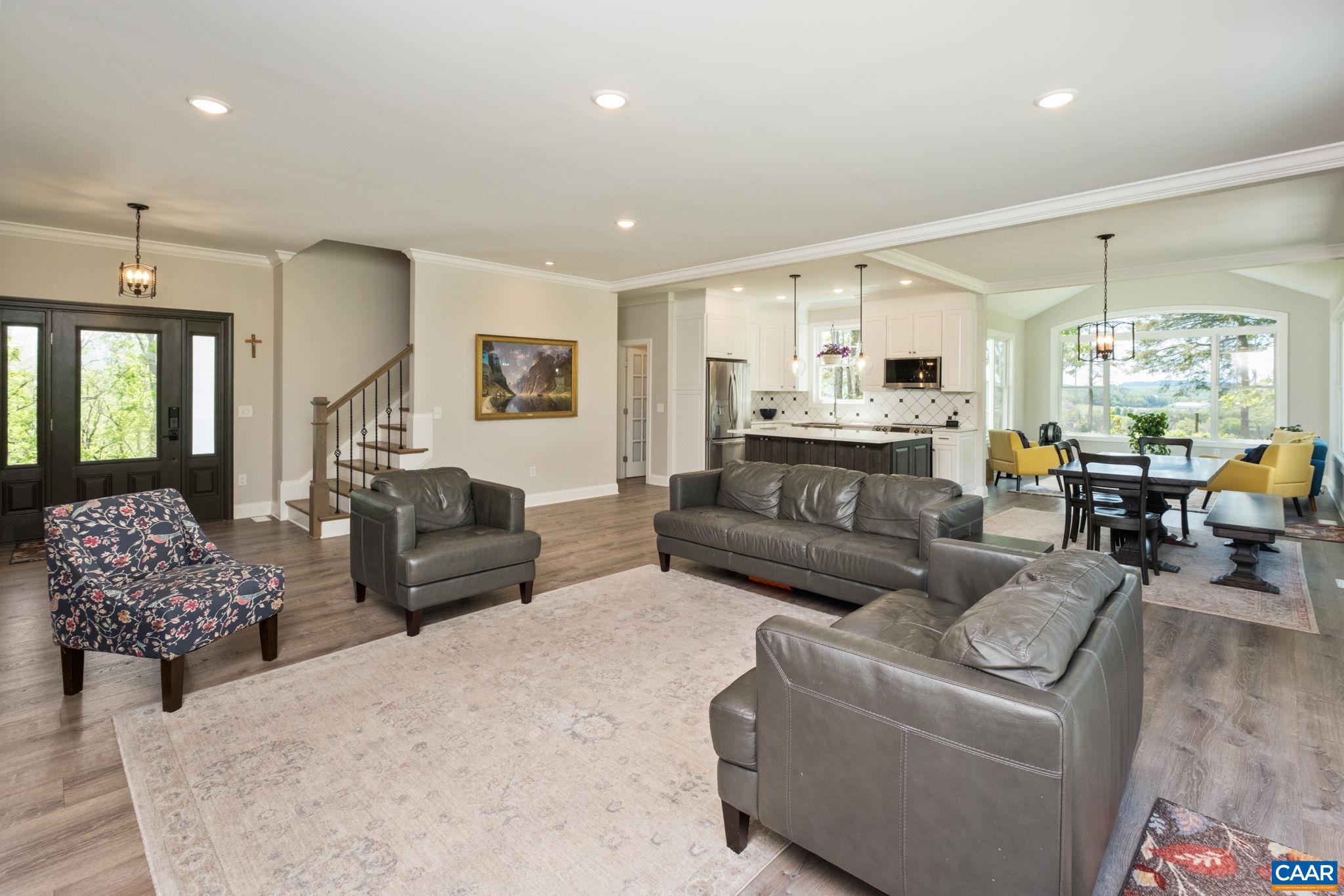 The living room is open to the kitchen, dining room, and sunroom, with large windows and doors to enjoy views.  A featured highlight is the coffered ceiling, and the custom built brick fireplace surround is a focal point of the space.