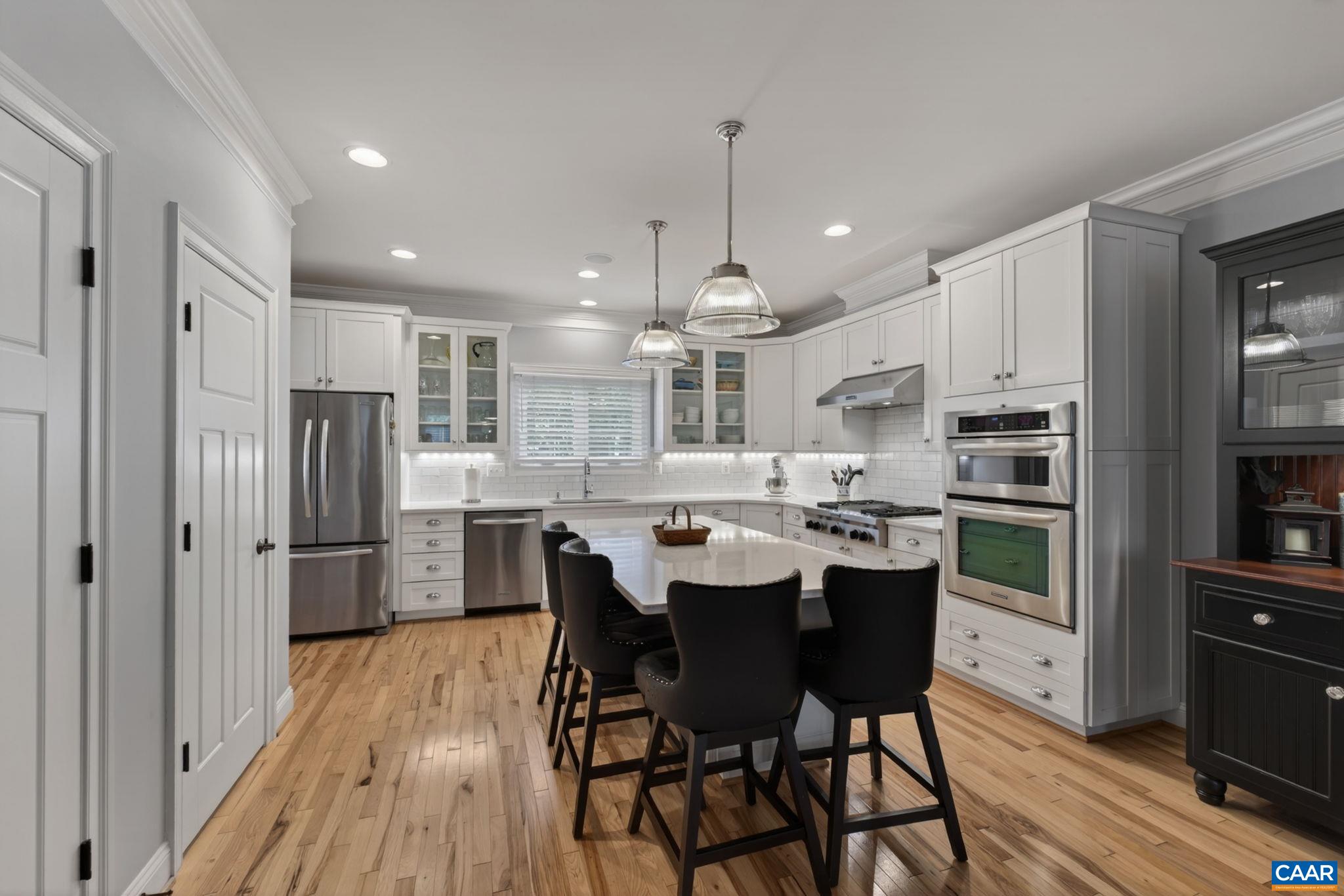 Gourmet kitchen with KitchenAid stainless appliances, quartz counters, pantry, eating island.
