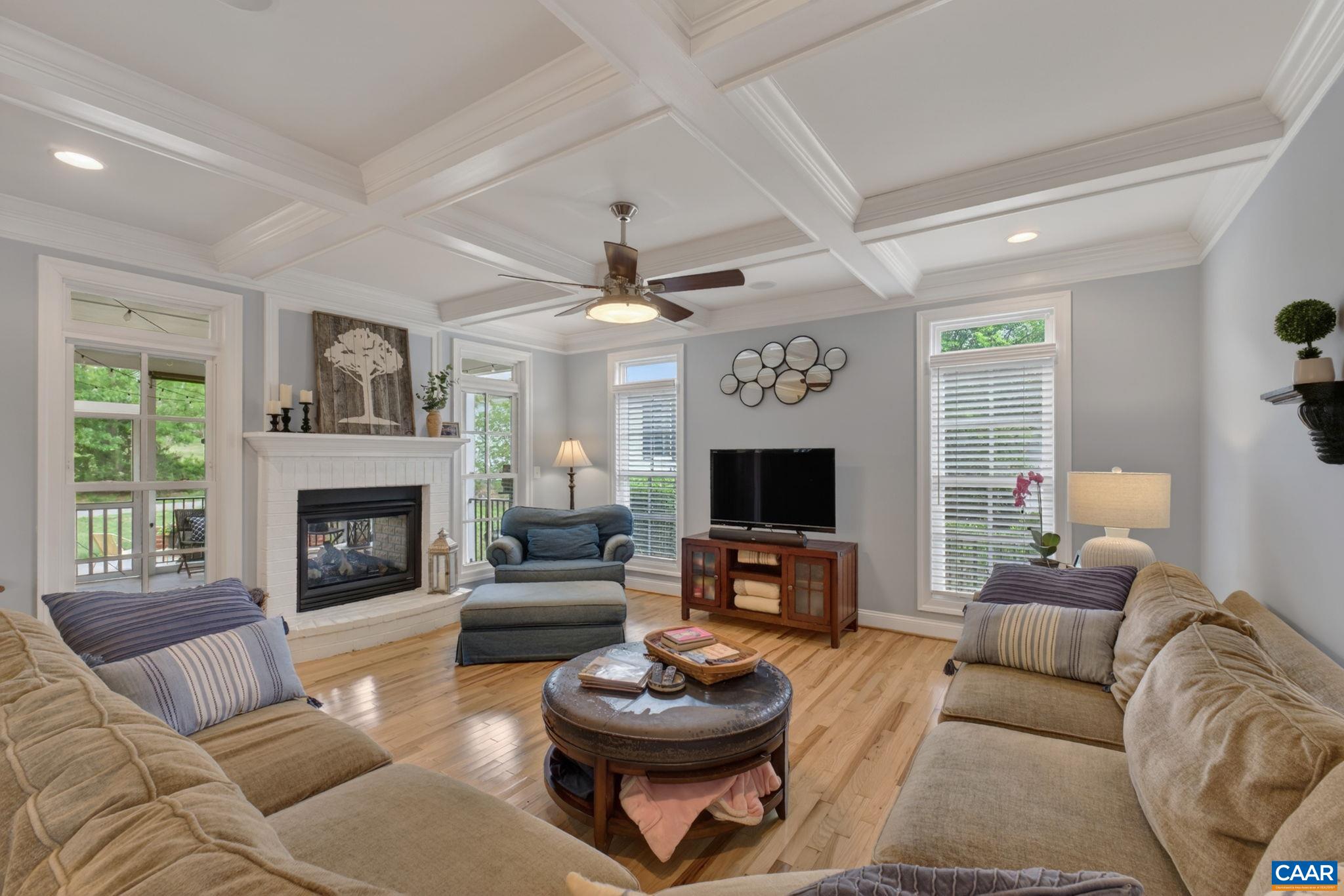 Large family room with coffered ceiling and indoor/outdoor fireplace.
