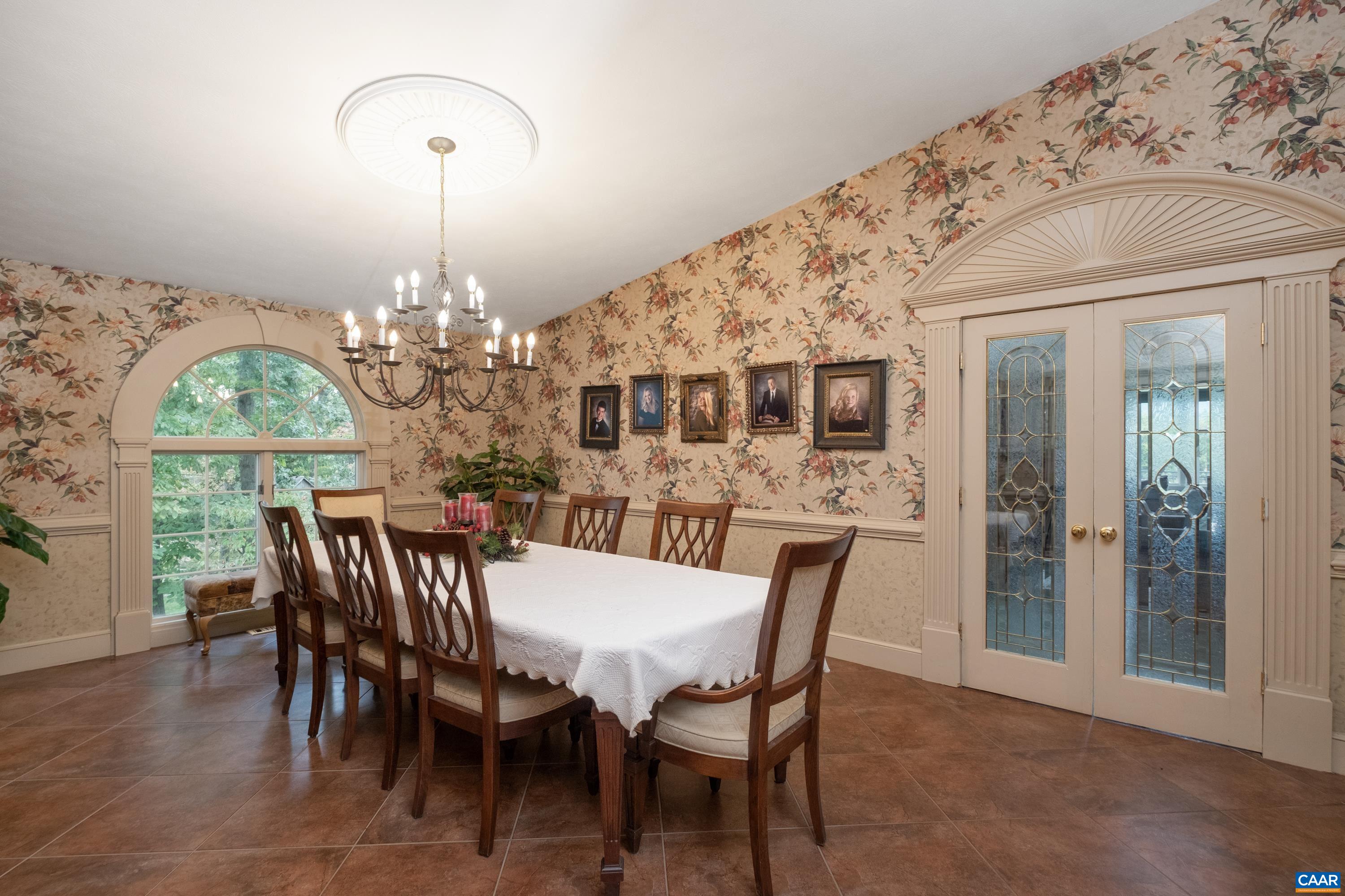 Alternate view of the dining room with French doors to the kitchen in view.  Window overlooks the luxurious and immaculately maintained grounds.