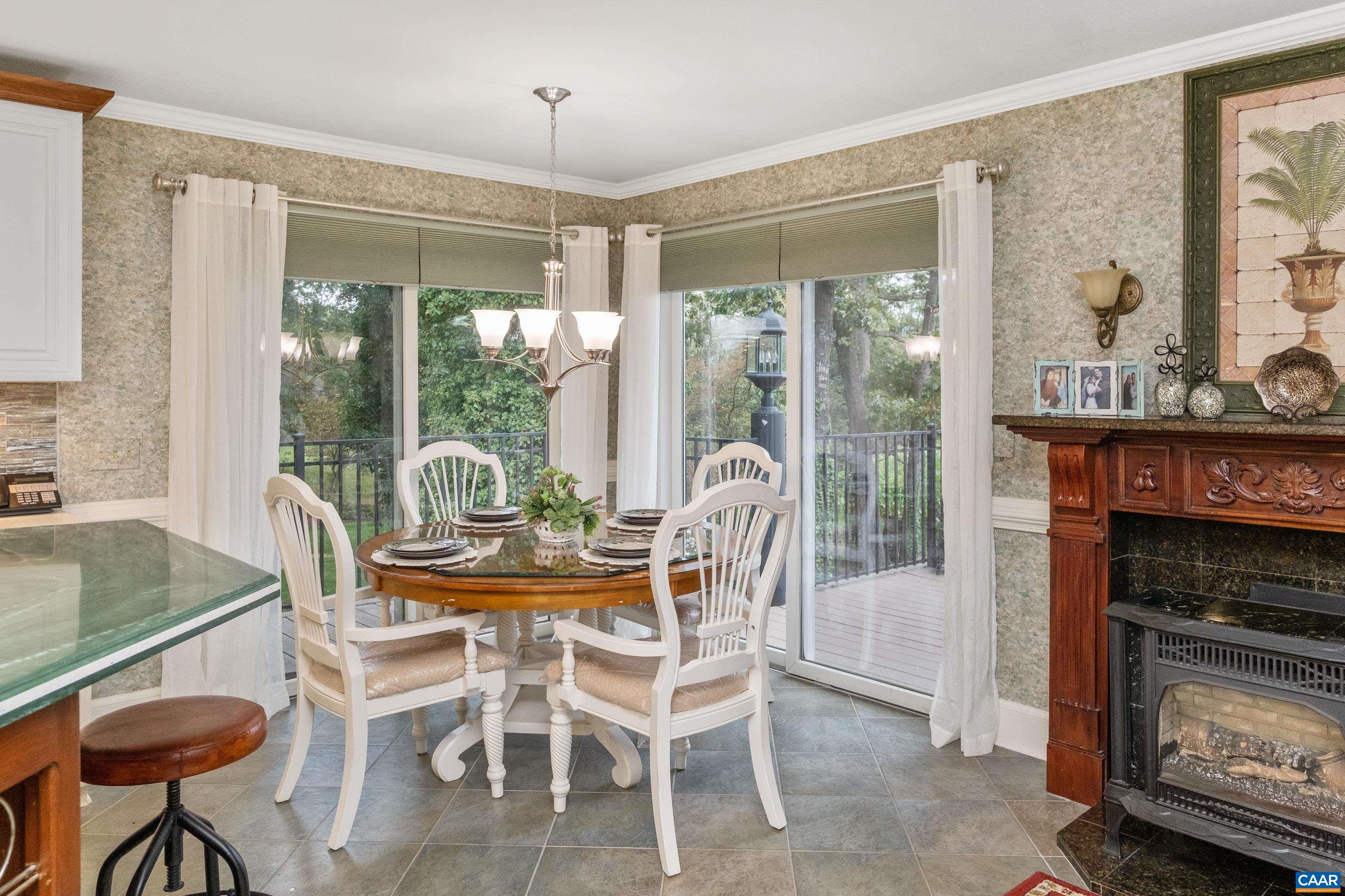 The kitchen also features a breakfast nook area, with access to a second level deck that wraps from the back to the side of the house, with views of the mountains and lush landscaping.  Fireplace also in view.