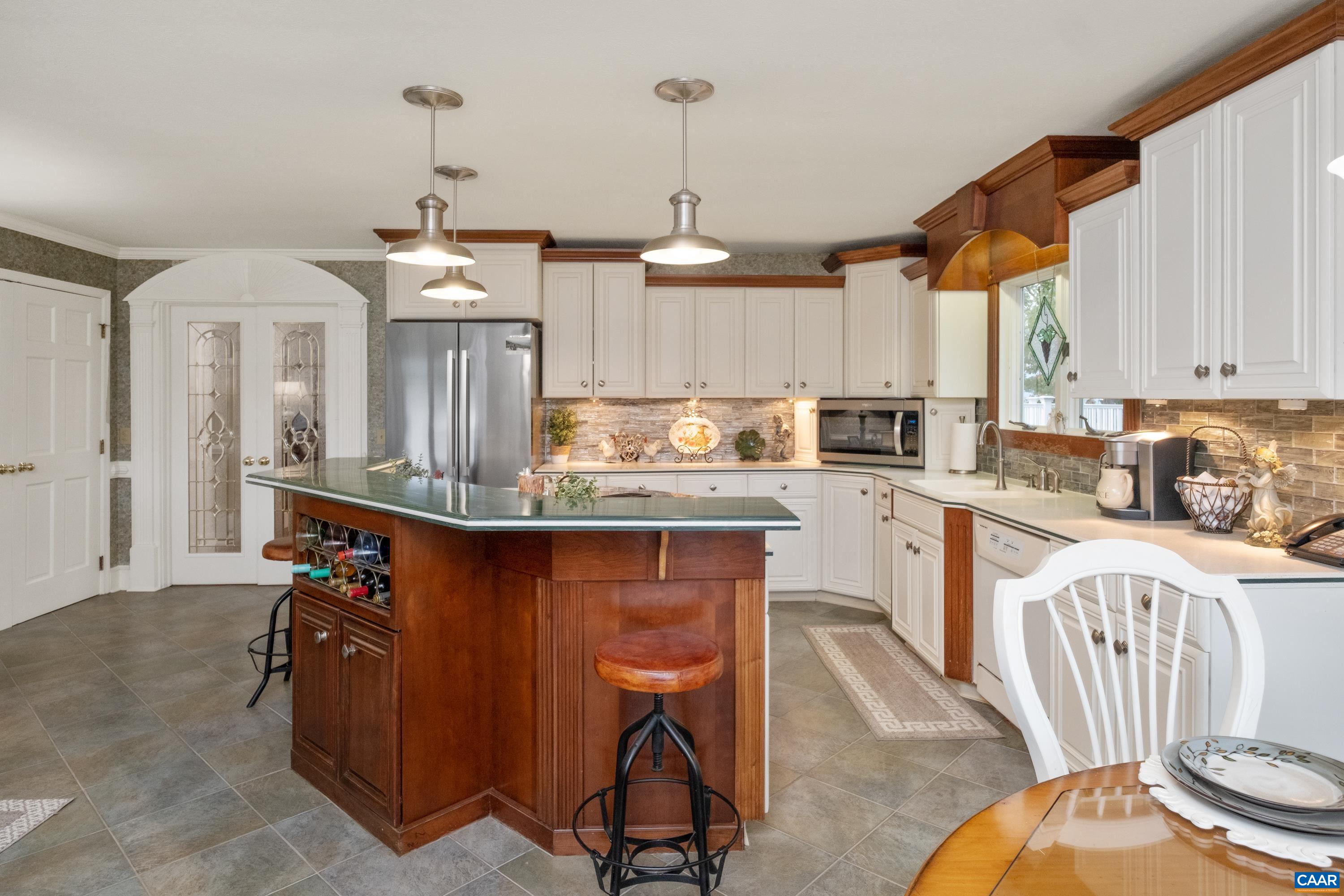 Alternate view of the kitchen with wine rack, TV cabinet, and pantry in view.  The dining room is through the French doors.