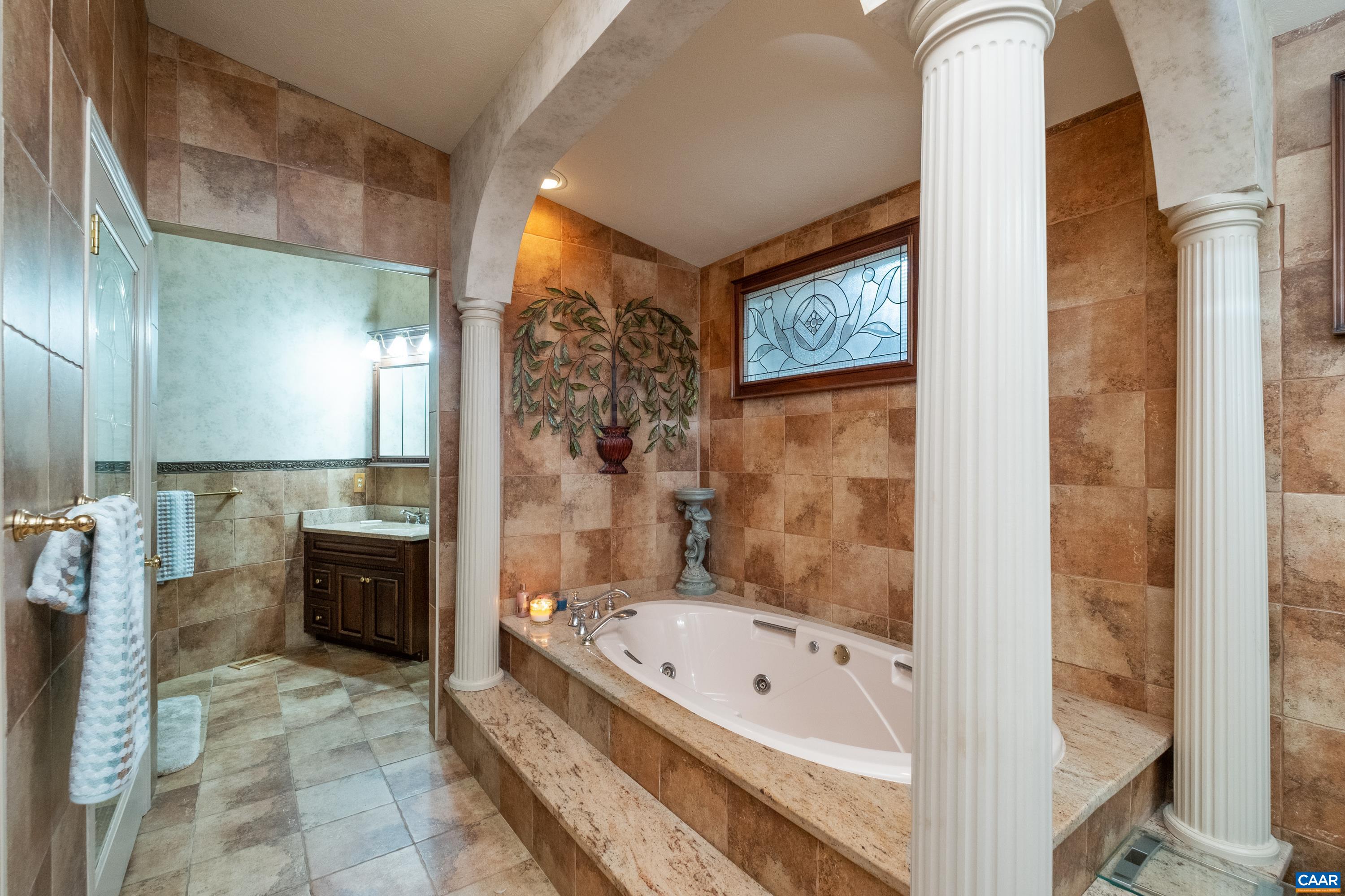 Ensuite bathroom is adorned by a jetted tub that is surrounded by pillars, and dual vanities (one sink/vanity on each end of the bathroom).