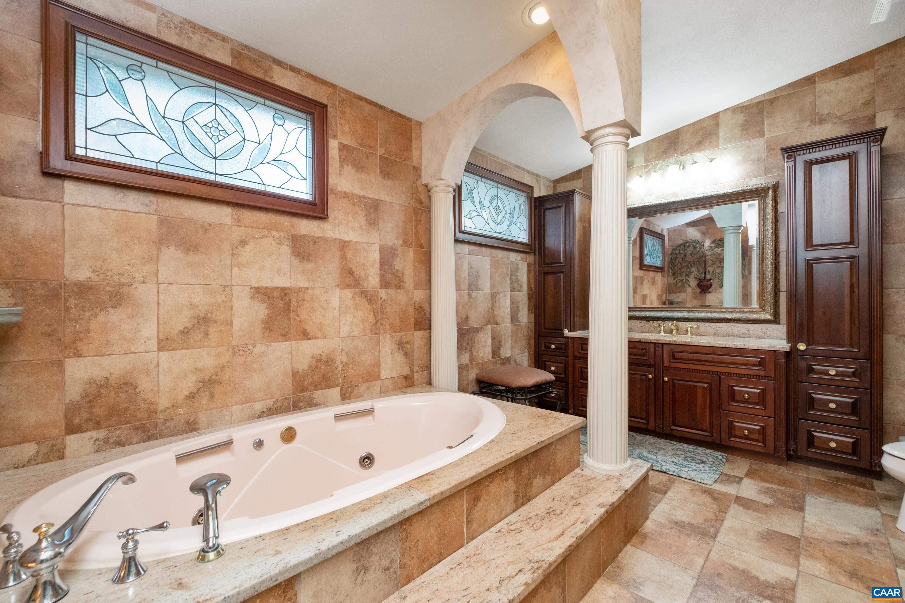 In view is one of the vanity/sink locations, with custom cherry cabinetry.  The other vanity/sink location, tiled shower, and walk-in closet are located behind the camera.