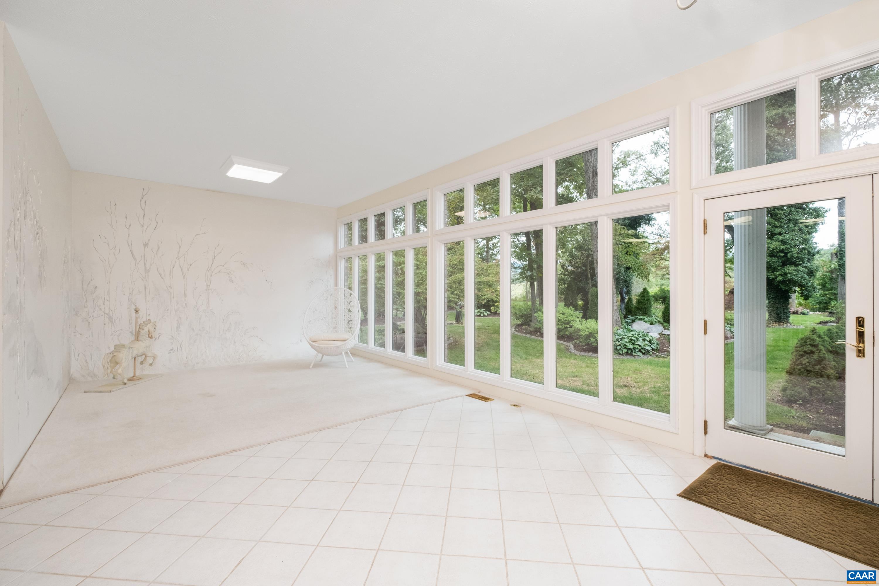 This bright sunroom was added to the property, and features floor to ceiling windows with transoms, French doors, and a brick and stone covered patio.
