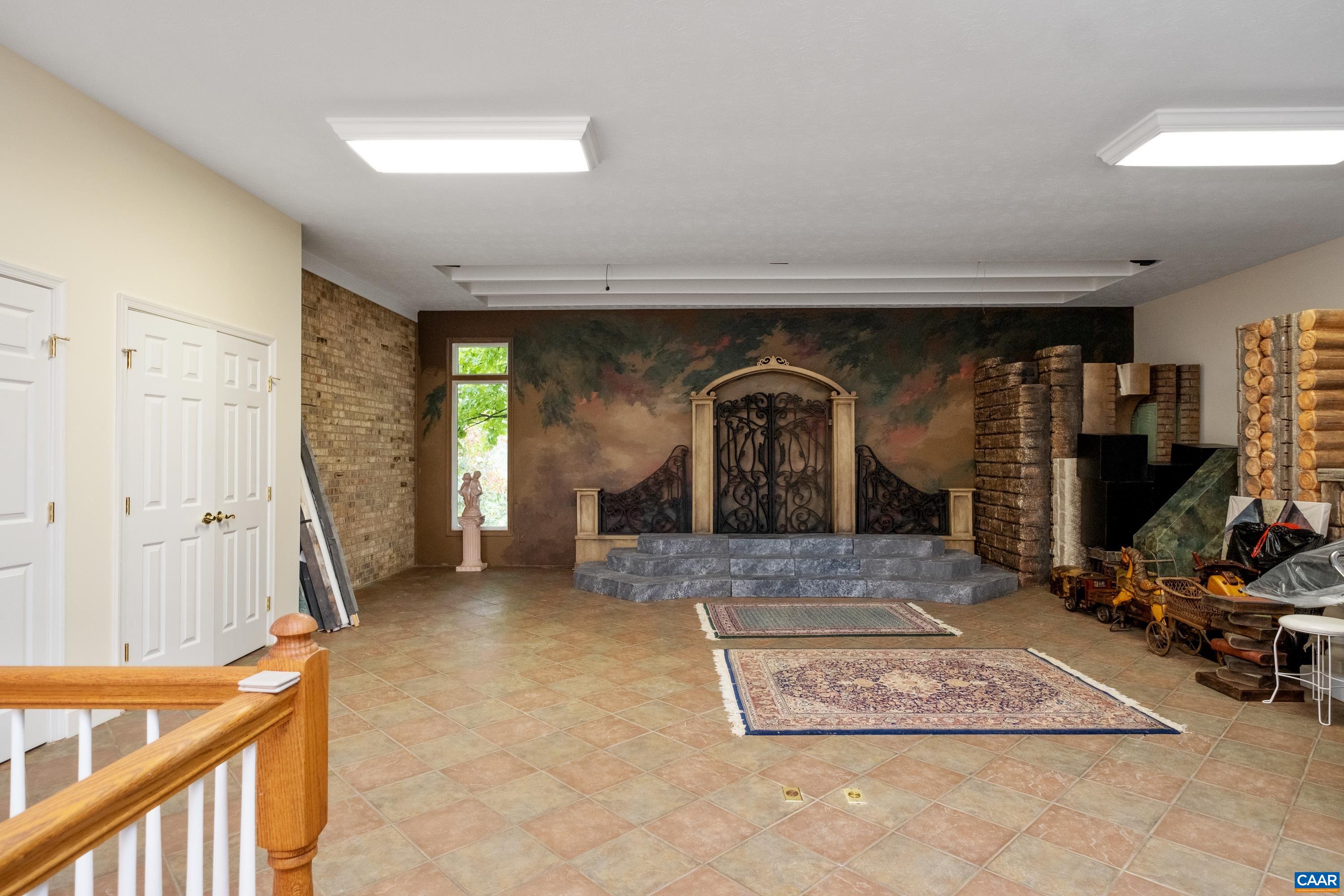 The bonus room is to the left of the sunroom, and features the quoin brickwork of the exterior.  The basement is under the sunroom/bonus room addition, and interior entrance stairs to the basement are in view.