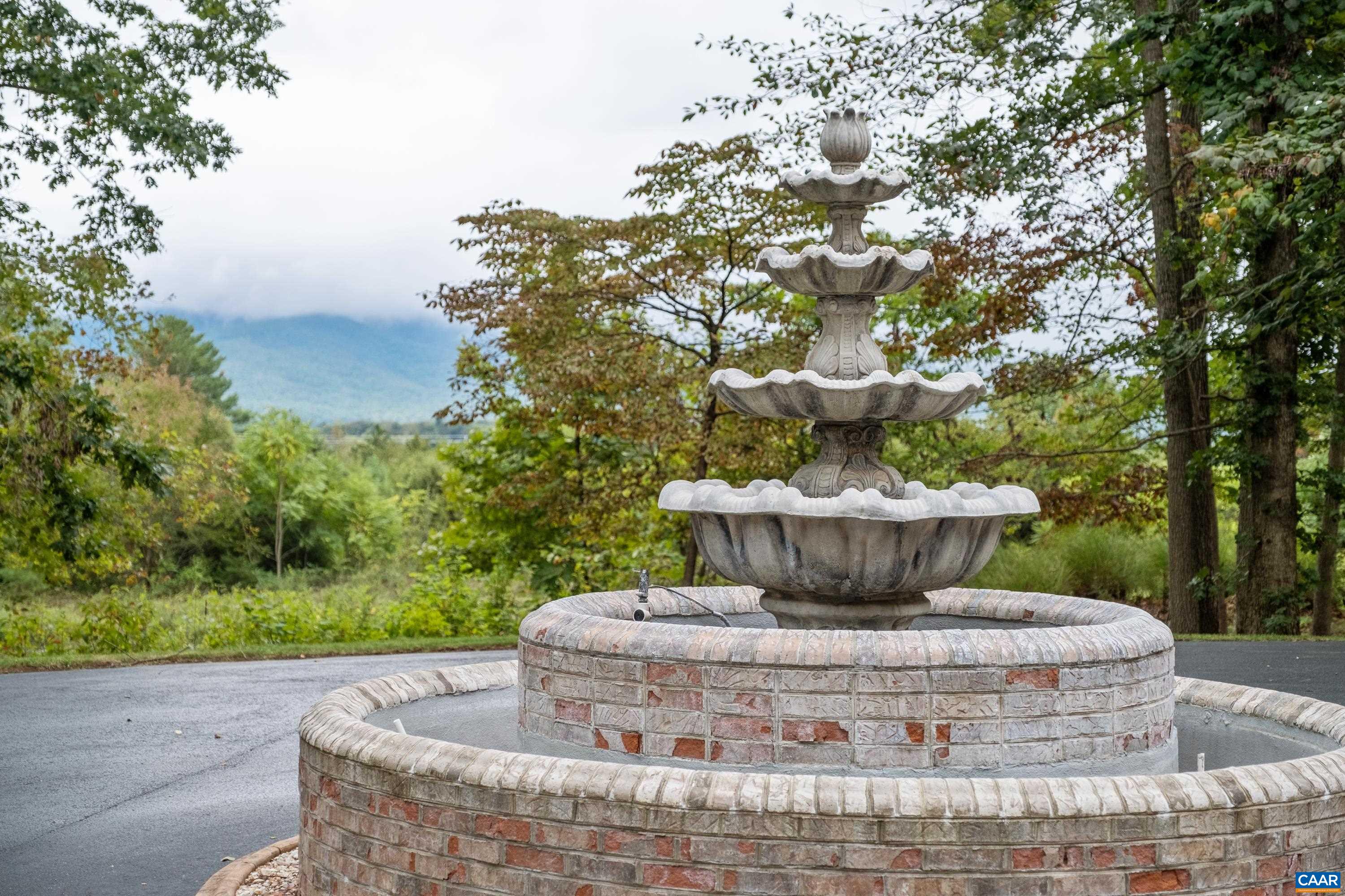The fountain adorns the circular driveway, with mountain views in the background.