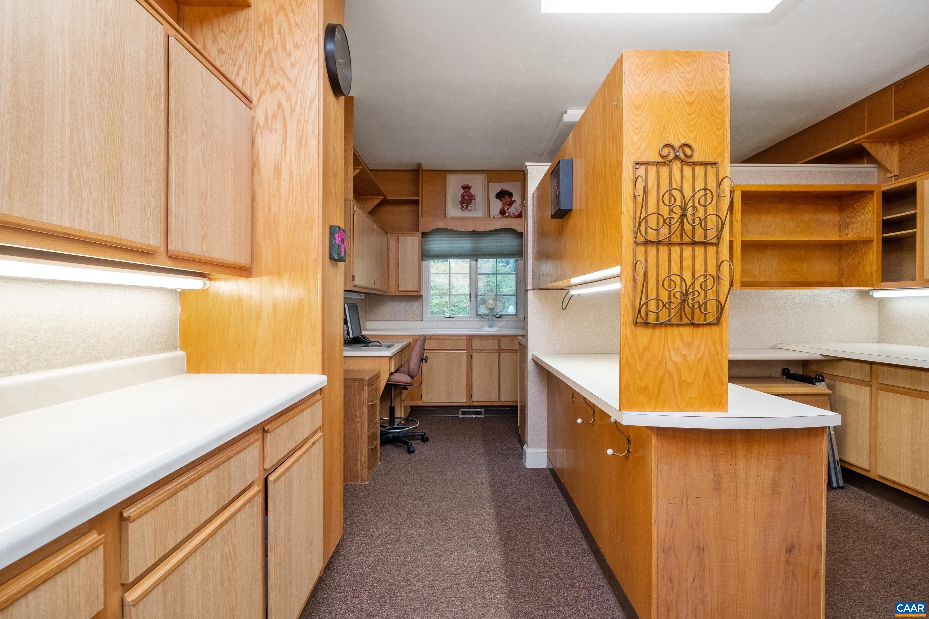 Another office with ample countertop workspace, a walk-in closet to the left, and an adjoining work room (not in view but to the right of the camera).